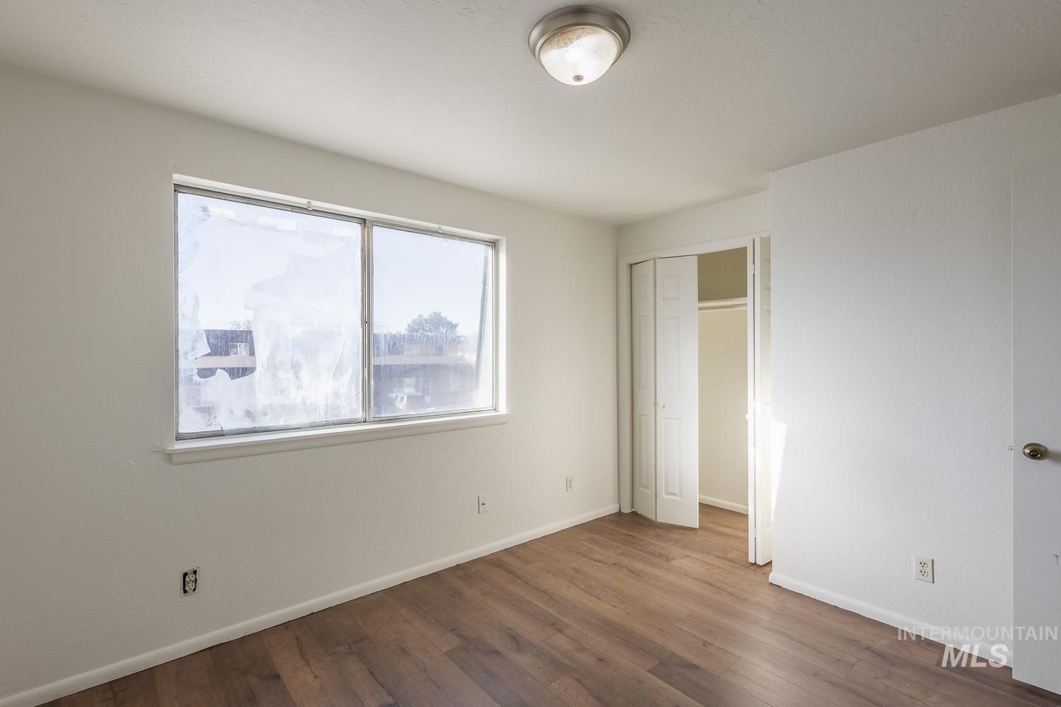Unfurnished bedroom with dark wood-style floors and a closet