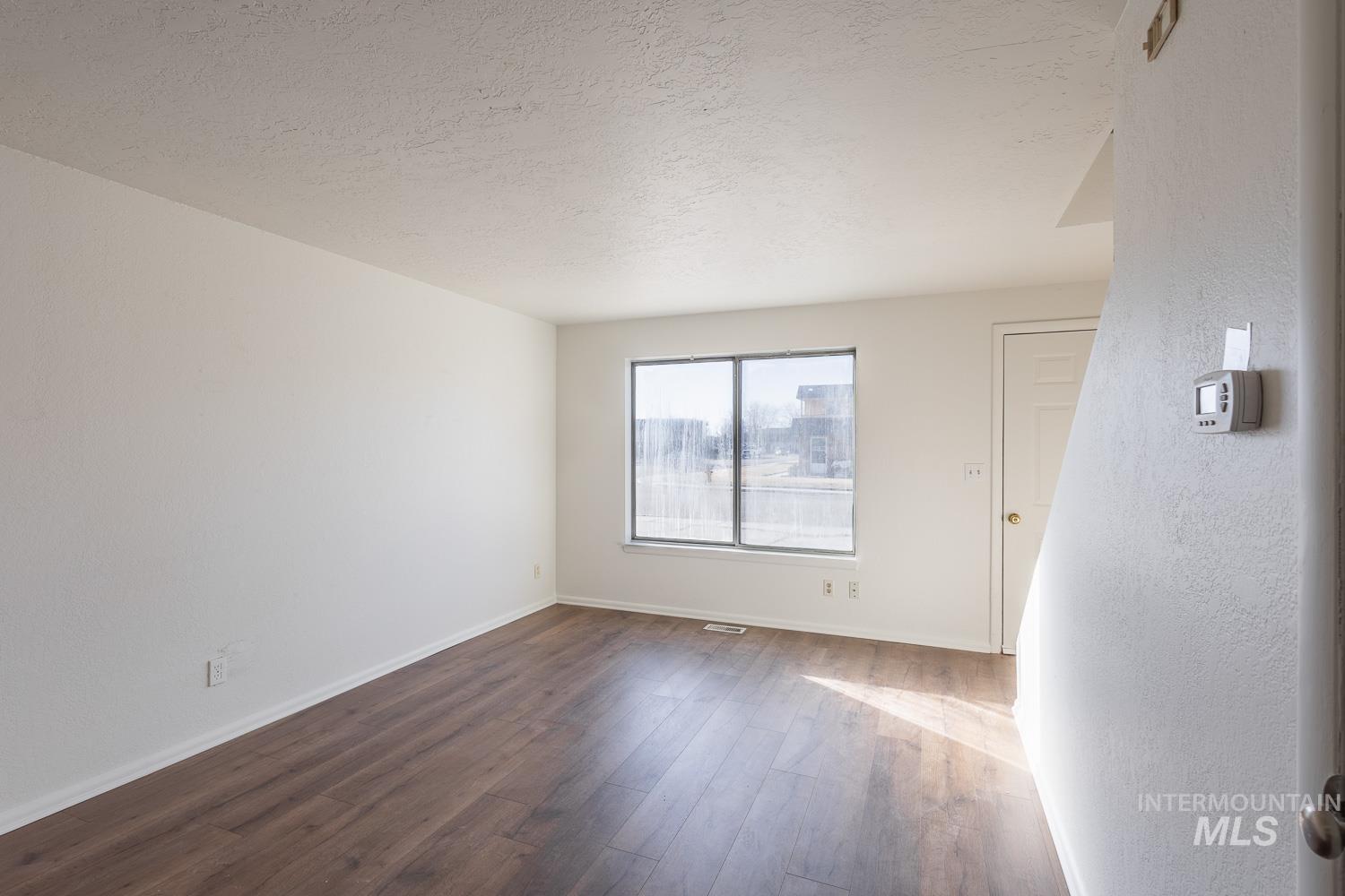Empty room featuring dark wood-style floors and a textured ceiling