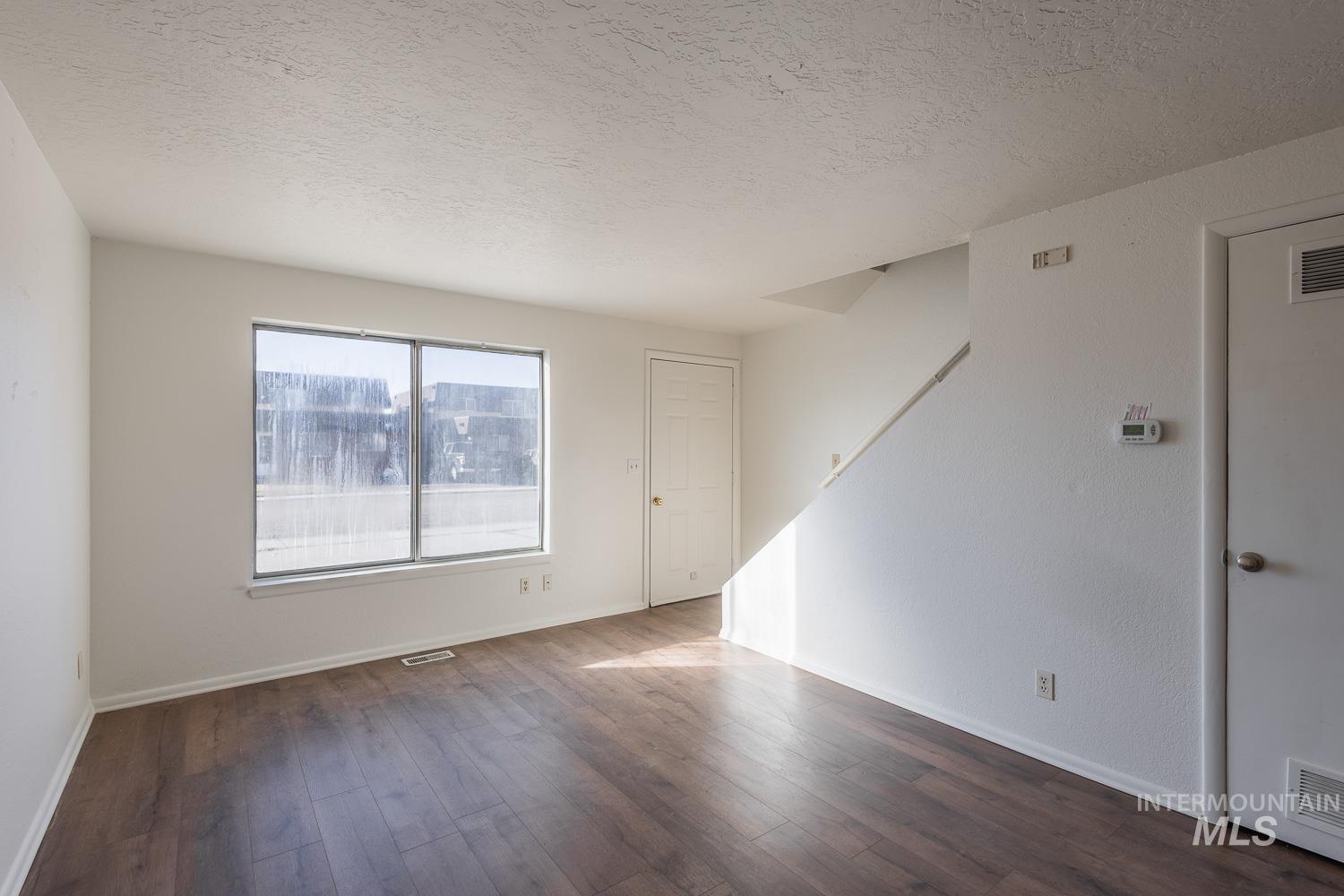 Empty room featuring dark wood-type flooring and a textured ceiling