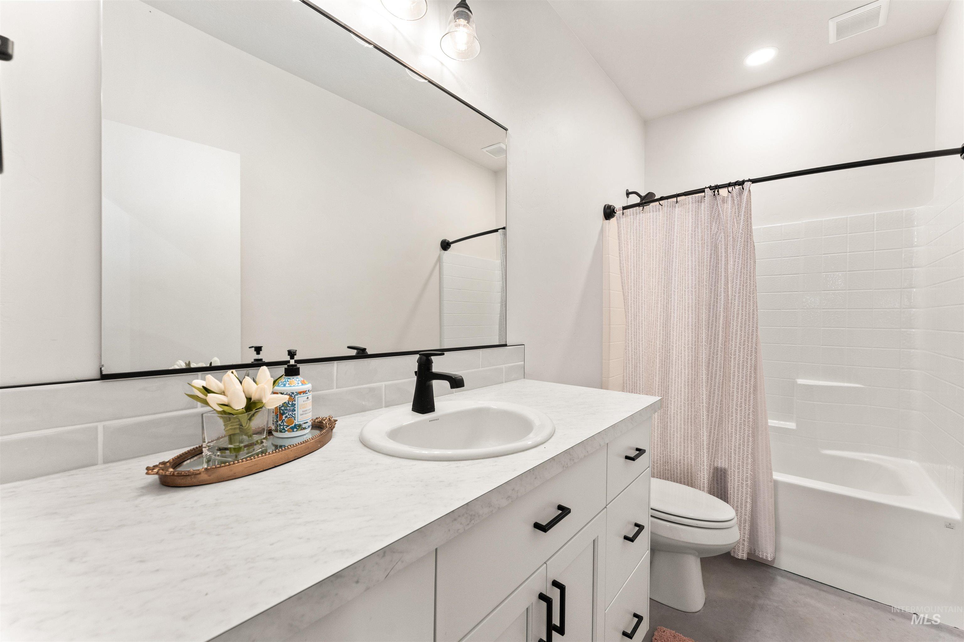 Bathroom with vanity, shower / bathtub combination with curtain, and recessed lighting