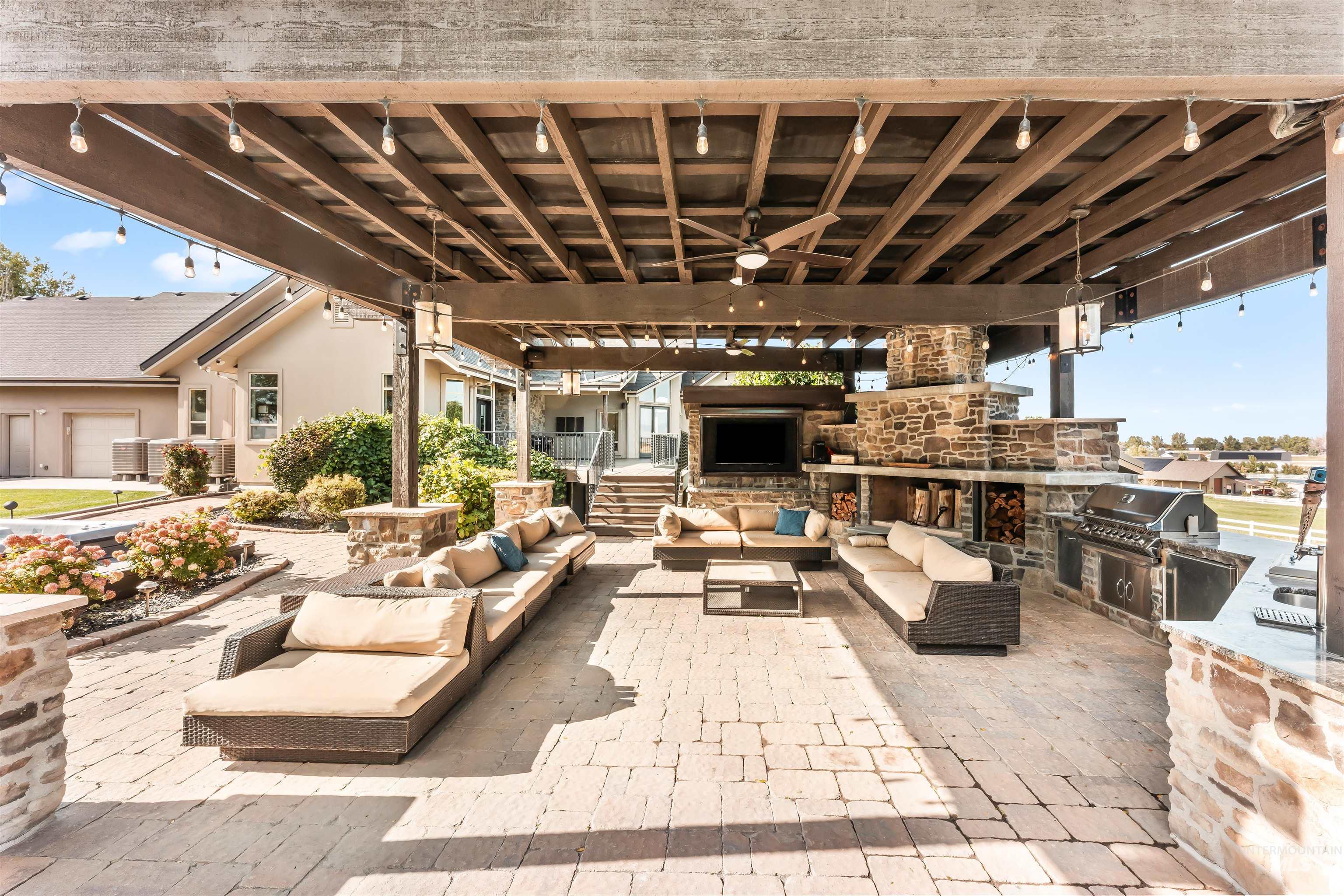 View of patio featuring an outdoor living space with a fireplace, an outdoor kitchen, and a ceiling fan