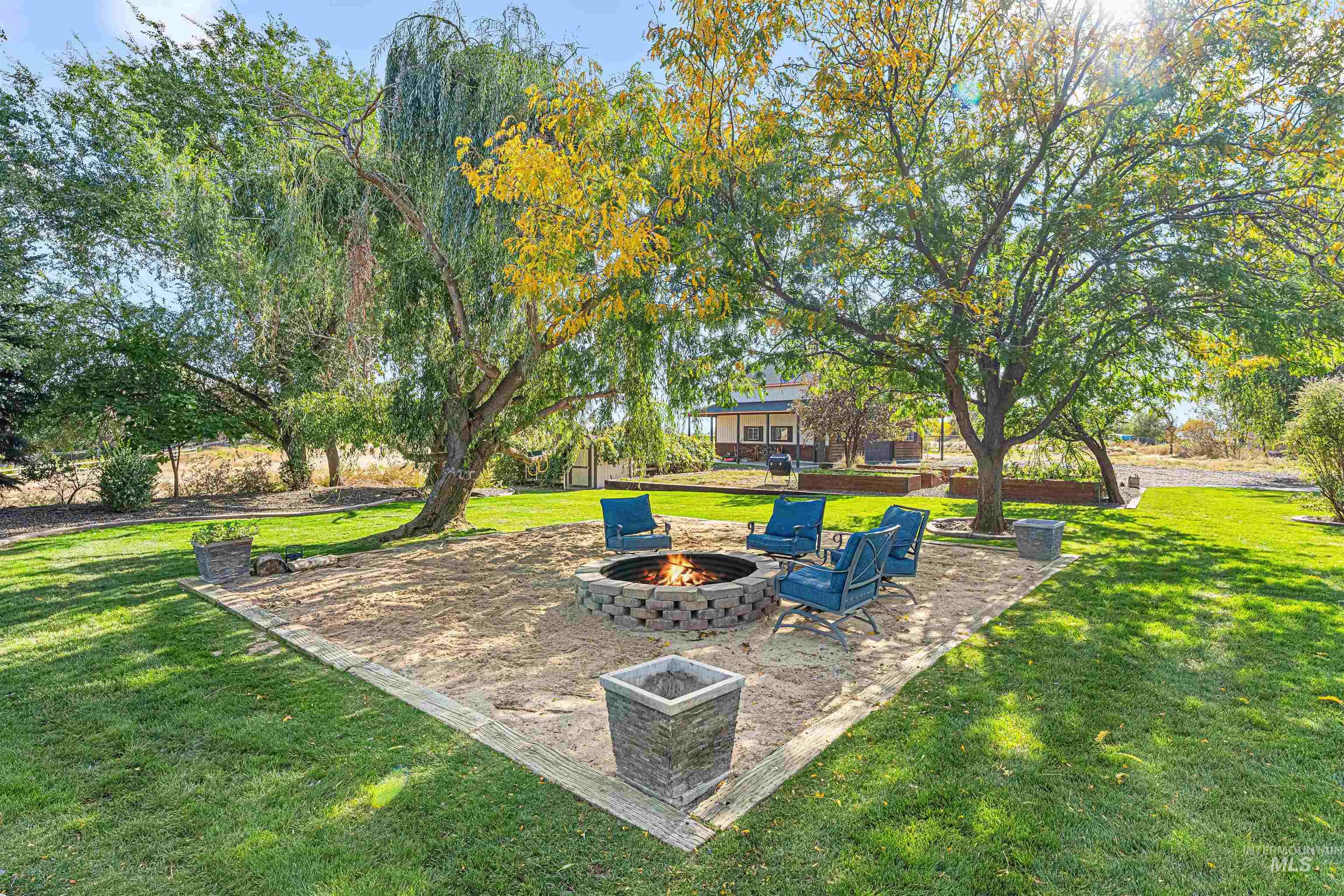 View of green lawn with a patio area and a fire pit
