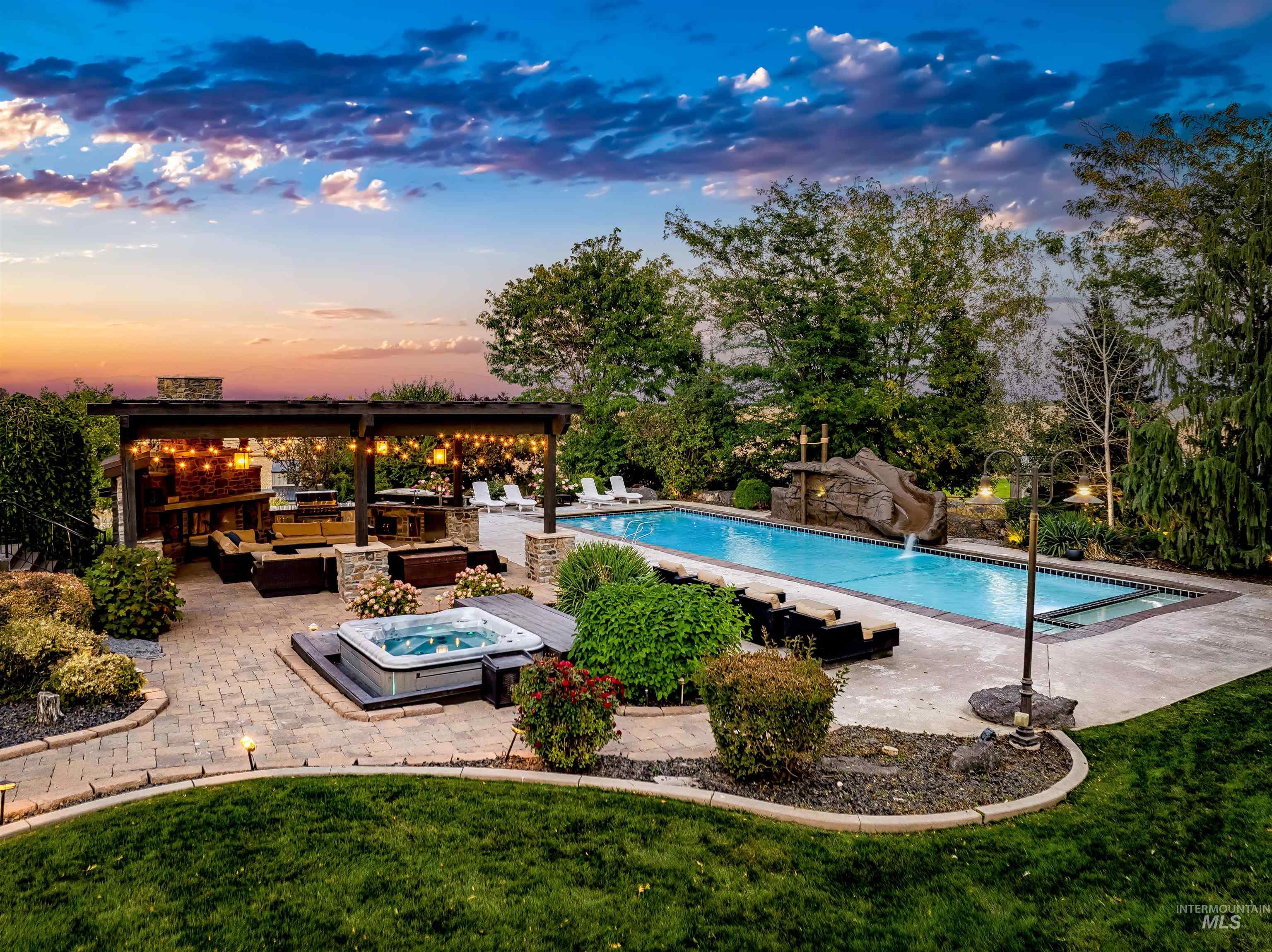 Pool at dusk with an outdoor hot tub, a patio, an outdoor pool, and an outdoor hangout area