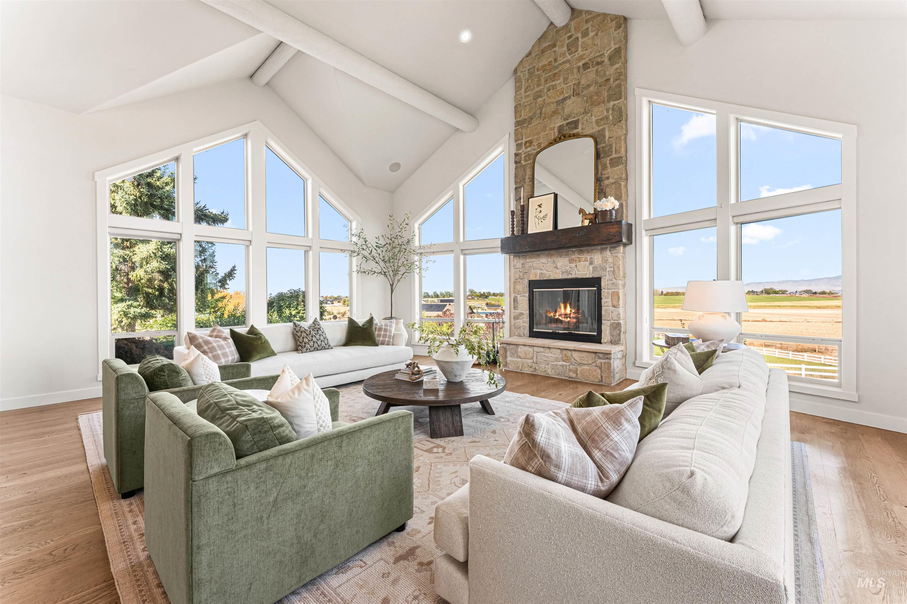 Living area with light wood-style flooring, high vaulted ceiling, a fireplace, and beamed ceiling