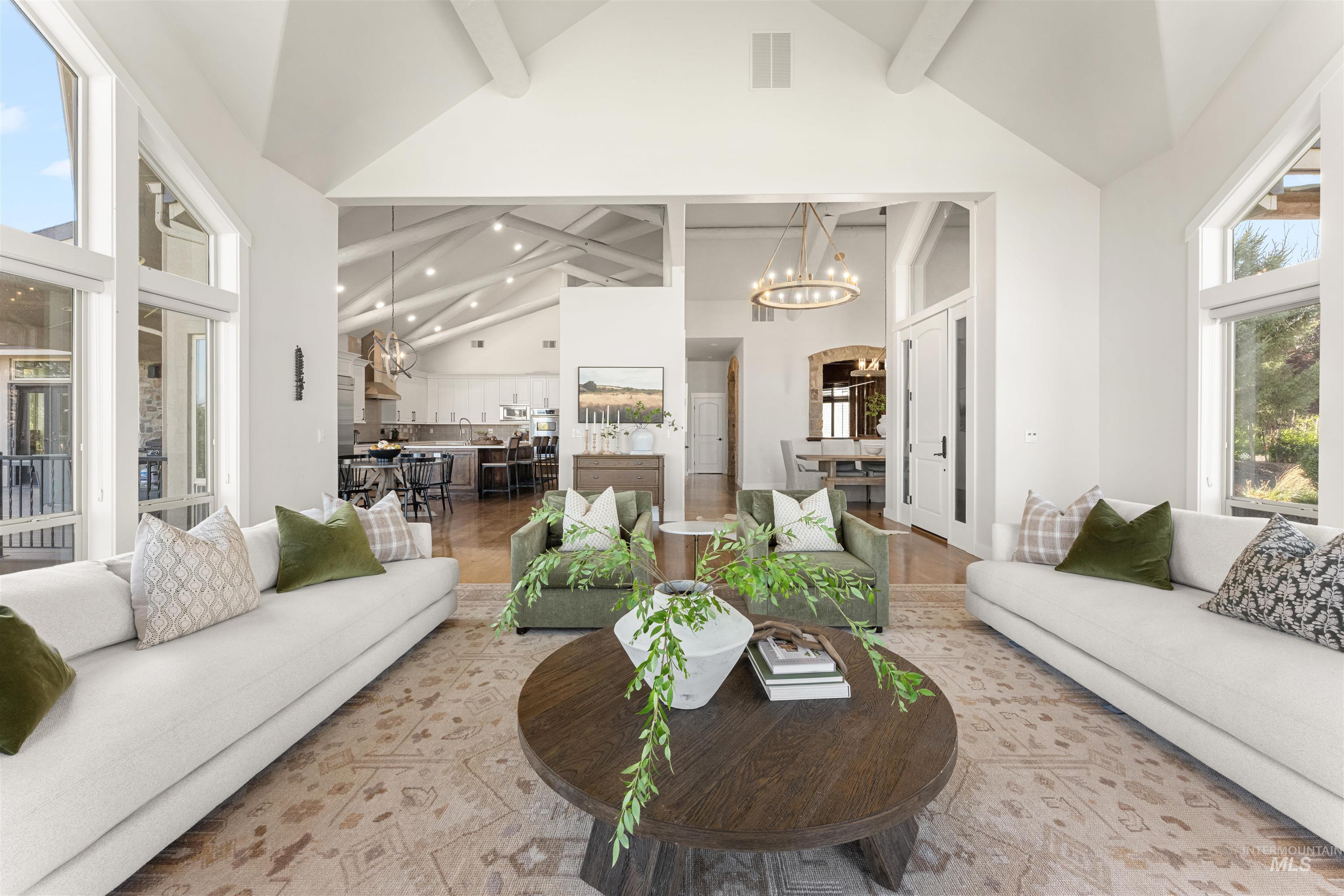 Living area with a chandelier, plenty of natural light, beamed ceiling, high vaulted ceiling, and recessed lighting