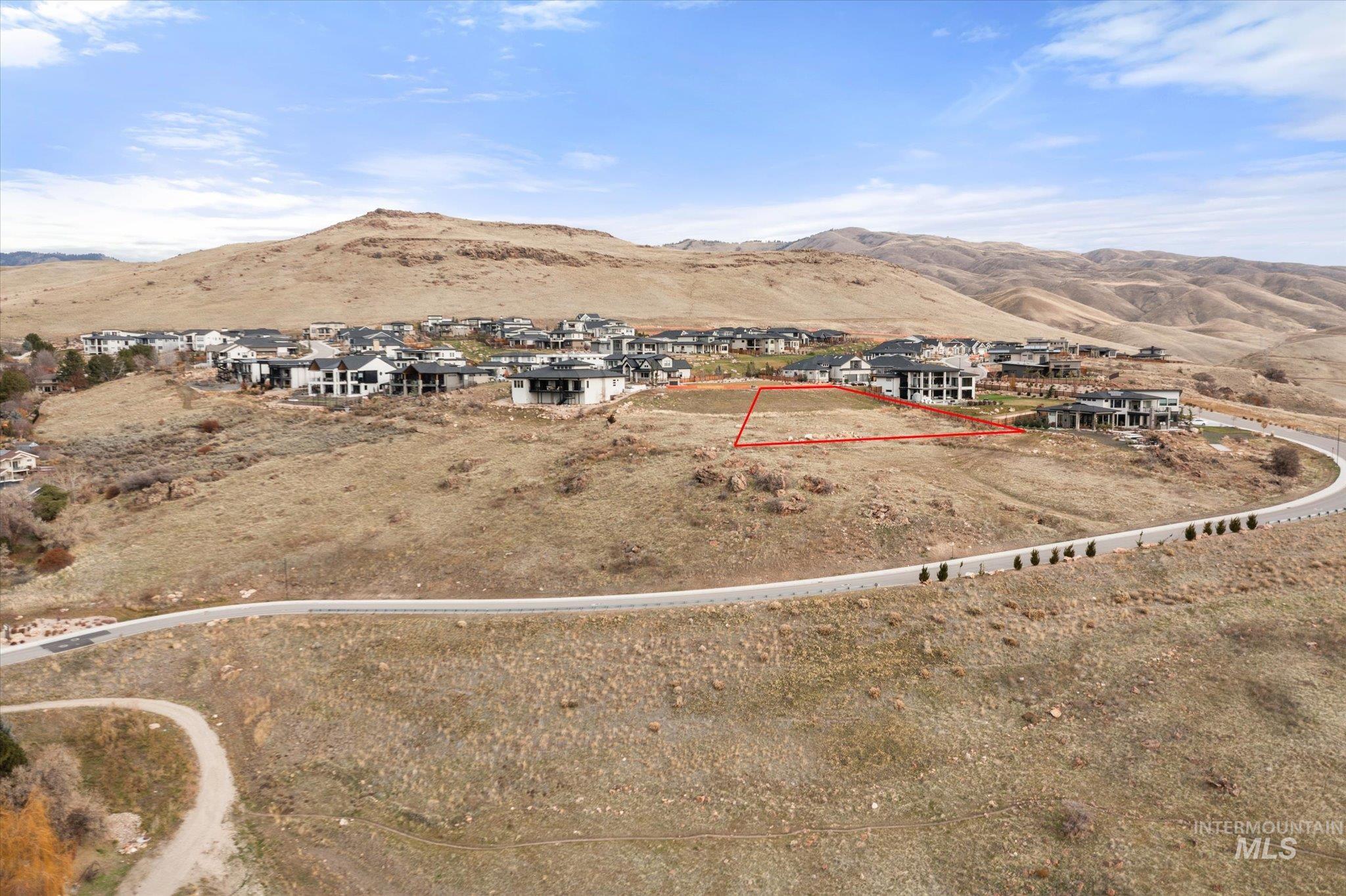 Aerial overview of property's location featuring nearby suburban area, mountains, and property boundaries highlighted