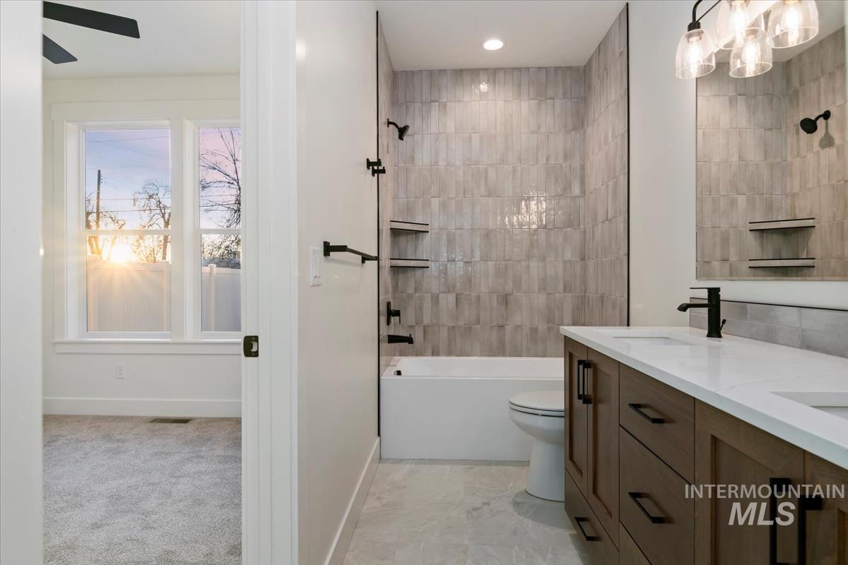 Bathroom featuring double vanity, tub / shower combination, light carpet, and a chandelier
