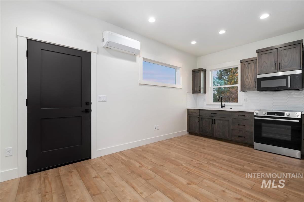 Kitchen with appliances with stainless steel finishes, light countertops, dark brown cabinetry, recessed lighting, and a wall mounted AC
