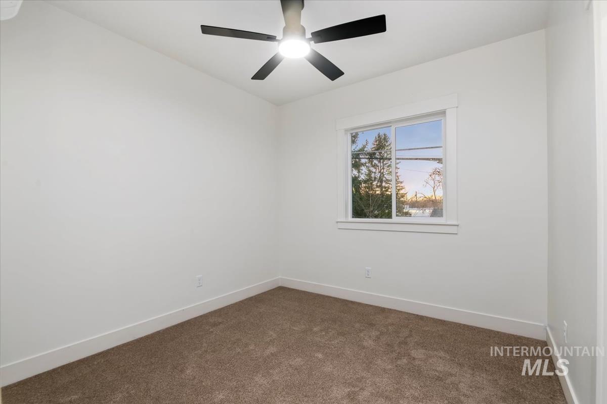 Empty room with dark colored carpet and baseboards