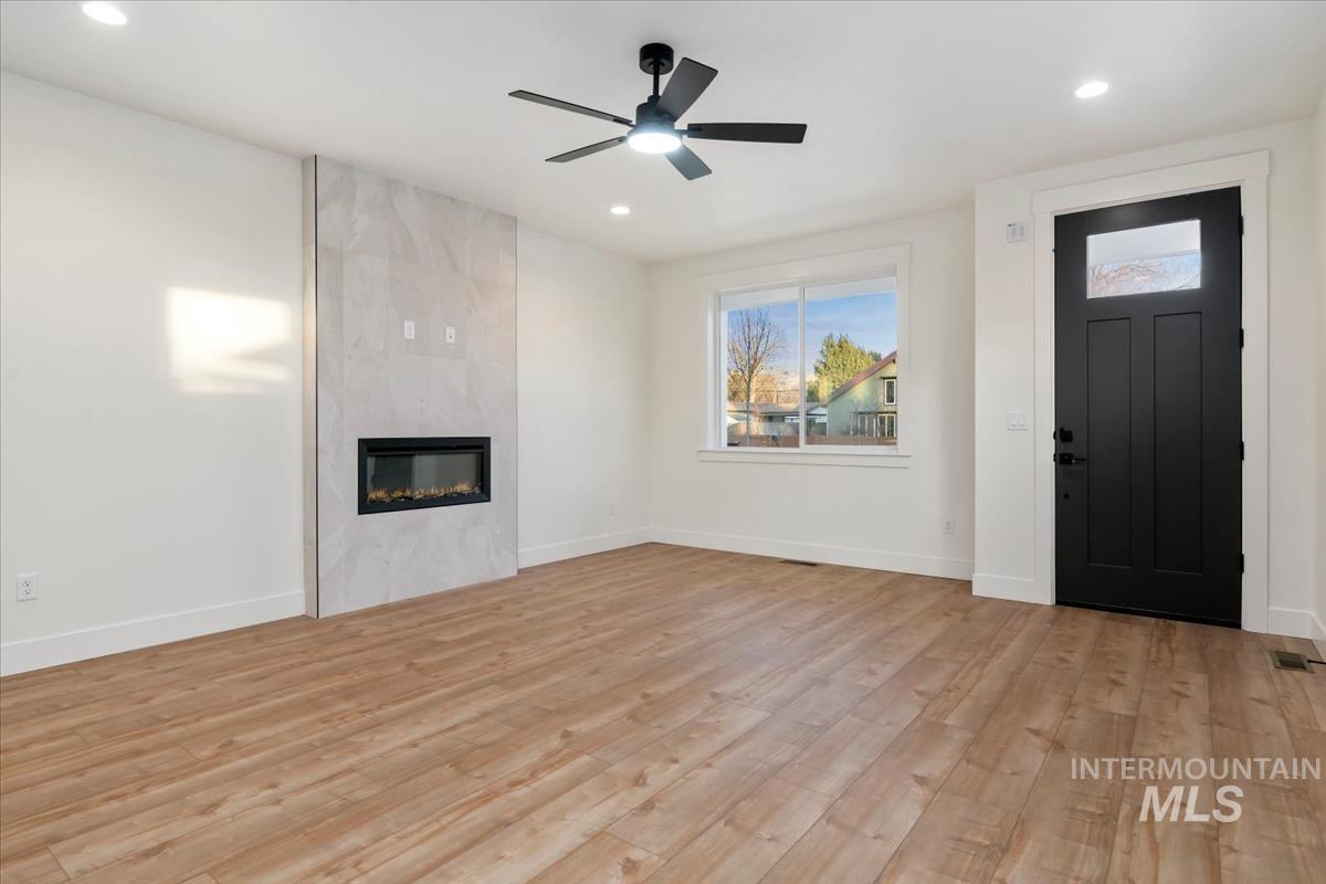 Unfurnished living room with light wood-style floors, a fireplace, a ceiling fan, and recessed lighting