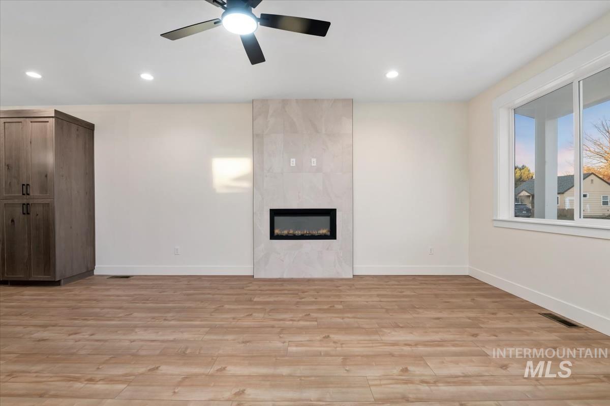 Unfurnished living room with recessed lighting, light wood-style flooring, a fireplace, and a ceiling fan
