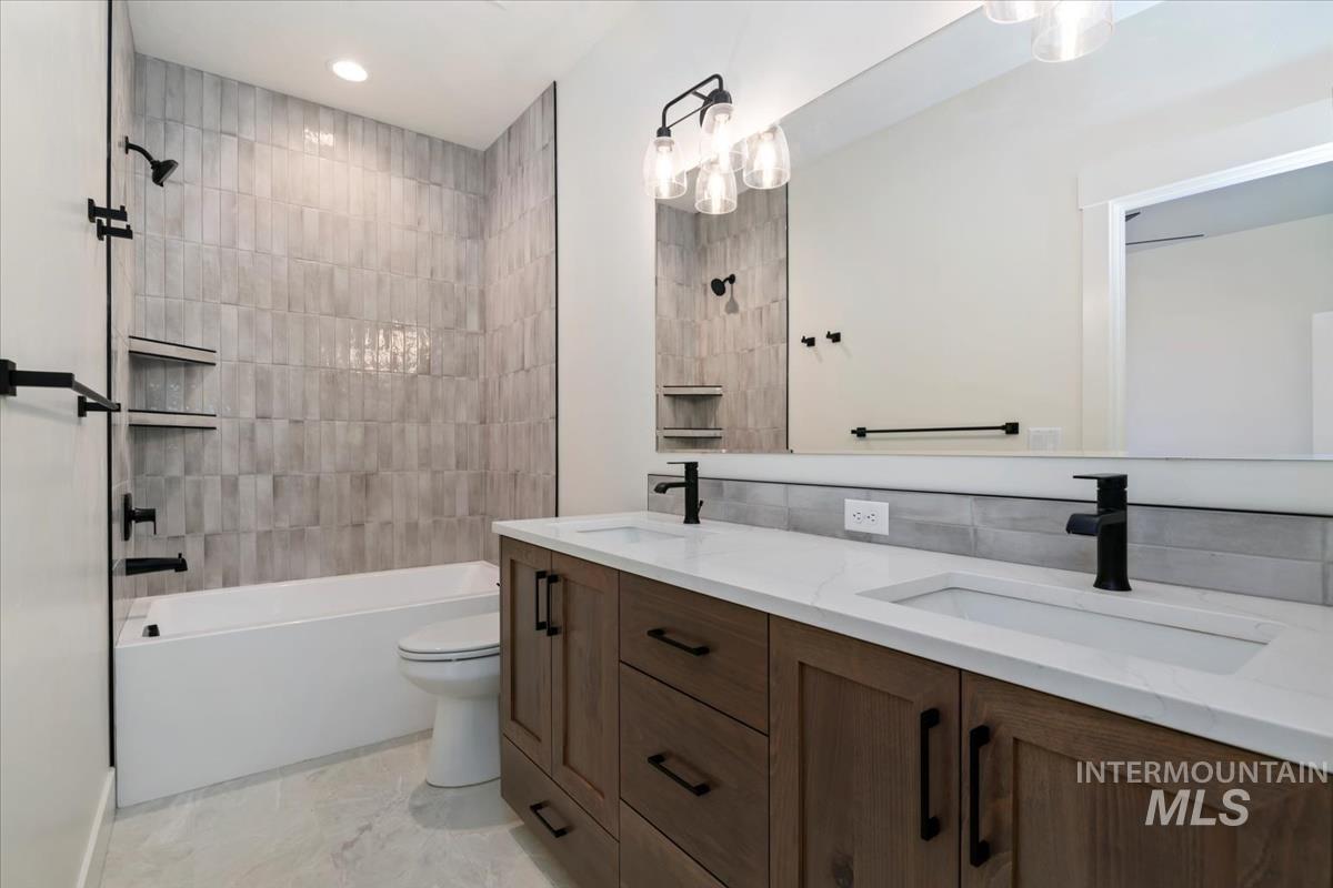 Full bath with double vanity, shower / washtub combination, and recessed lighting