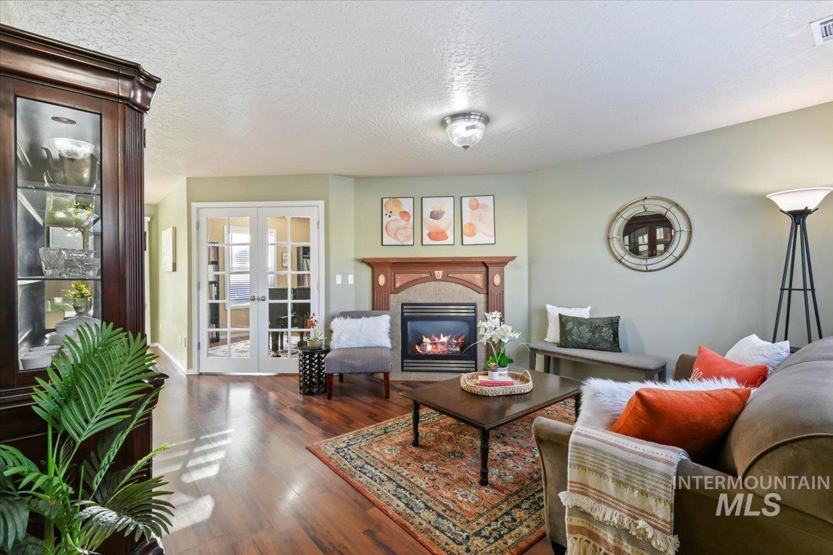 Living room with a glass covered fireplace, a textured ceiling, french doors, and wood finished floors