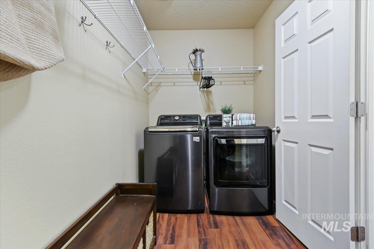 Washroom with washing machine and clothes dryer, dark wood-style flooring, and a textured ceiling
