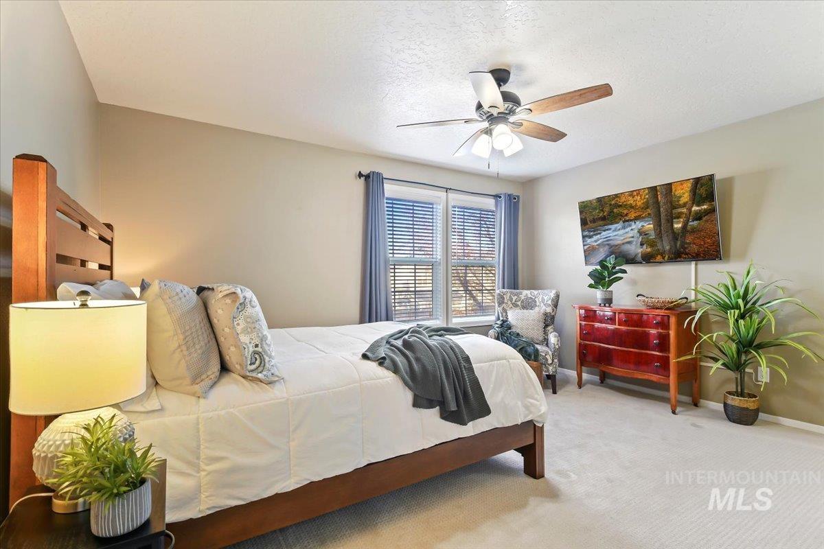 Carpeted bedroom with a ceiling fan and a textured ceiling