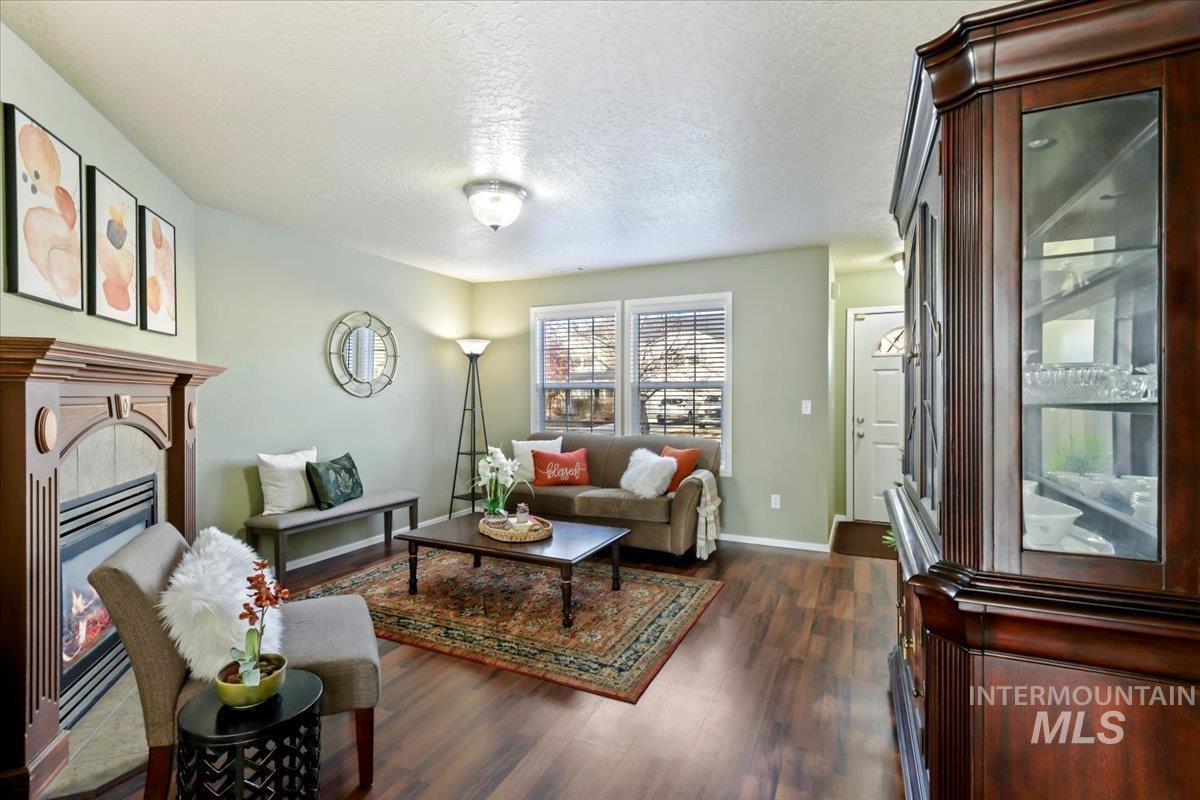 Living room with a glass covered fireplace, a textured ceiling, and dark wood-type flooring