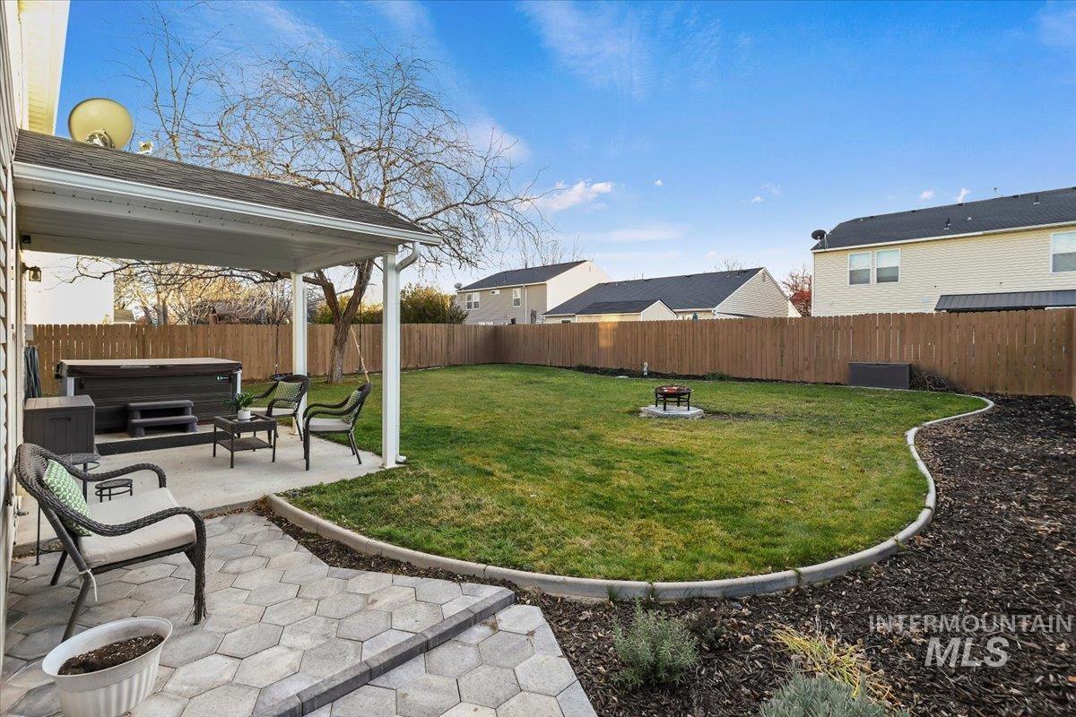Fenced backyard featuring a hot tub, a fire pit, and a patio area