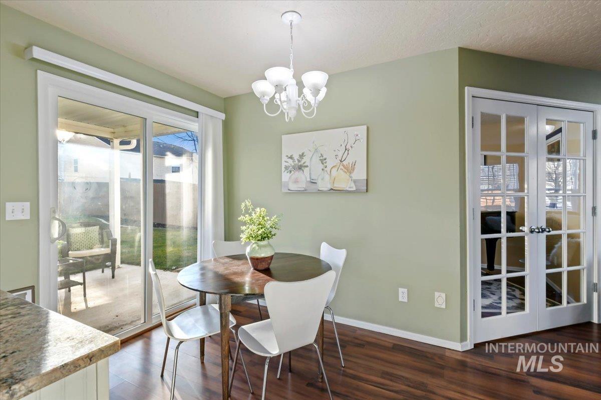 Dining space featuring french doors, a chandelier, and dark wood finished floors
