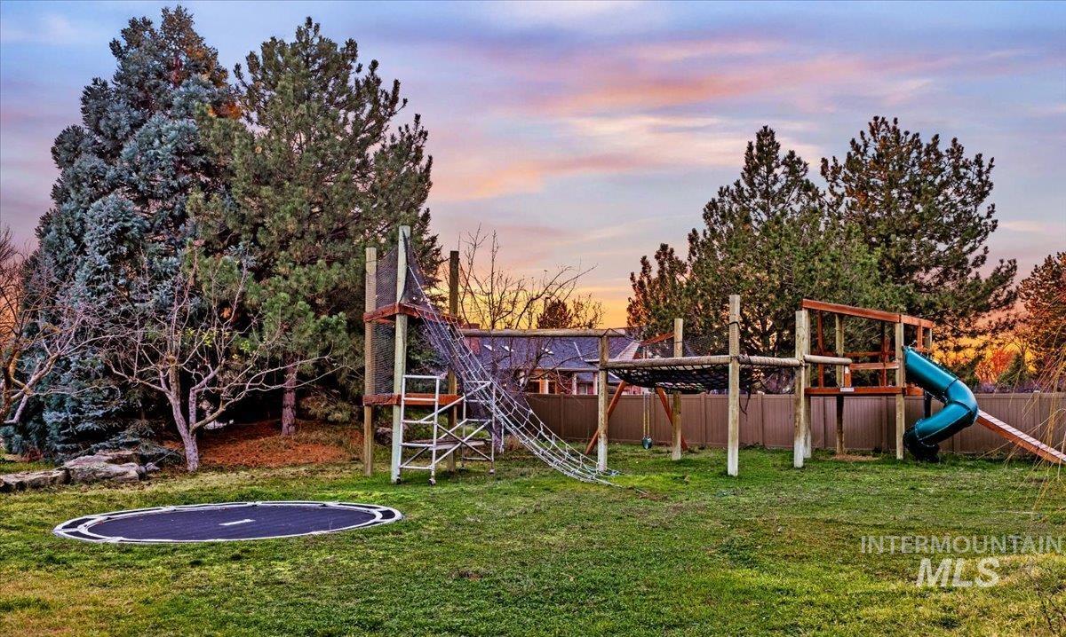 Yard at dusk with a playground and a trampoline