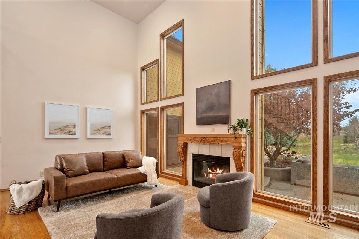 Living room featuring a tile fireplace, a high ceiling, and light wood-type flooring