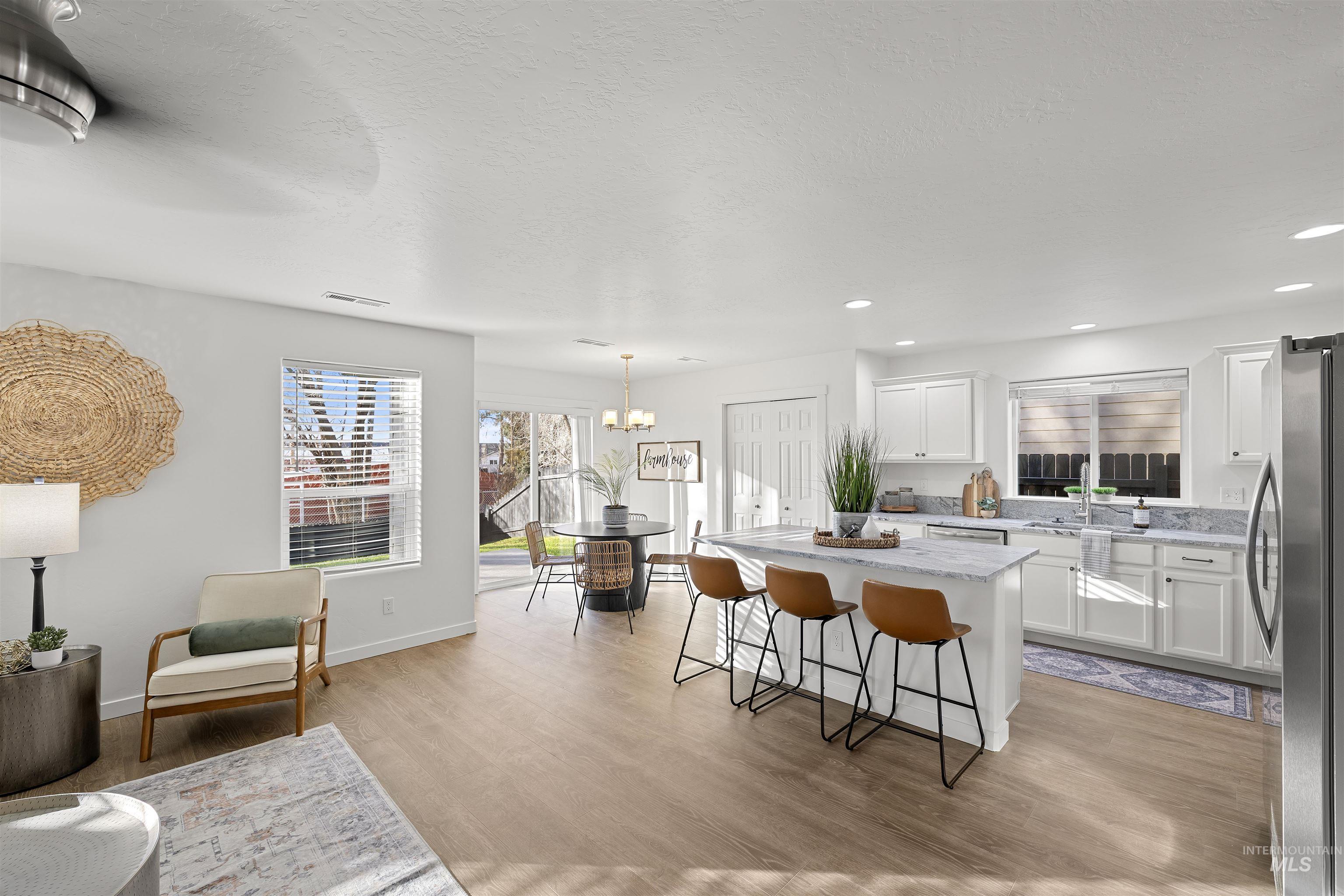 Kitchen featuring a kitchen island, white cabinets, a kitchen bar, freestanding refrigerator, and a textured ceiling