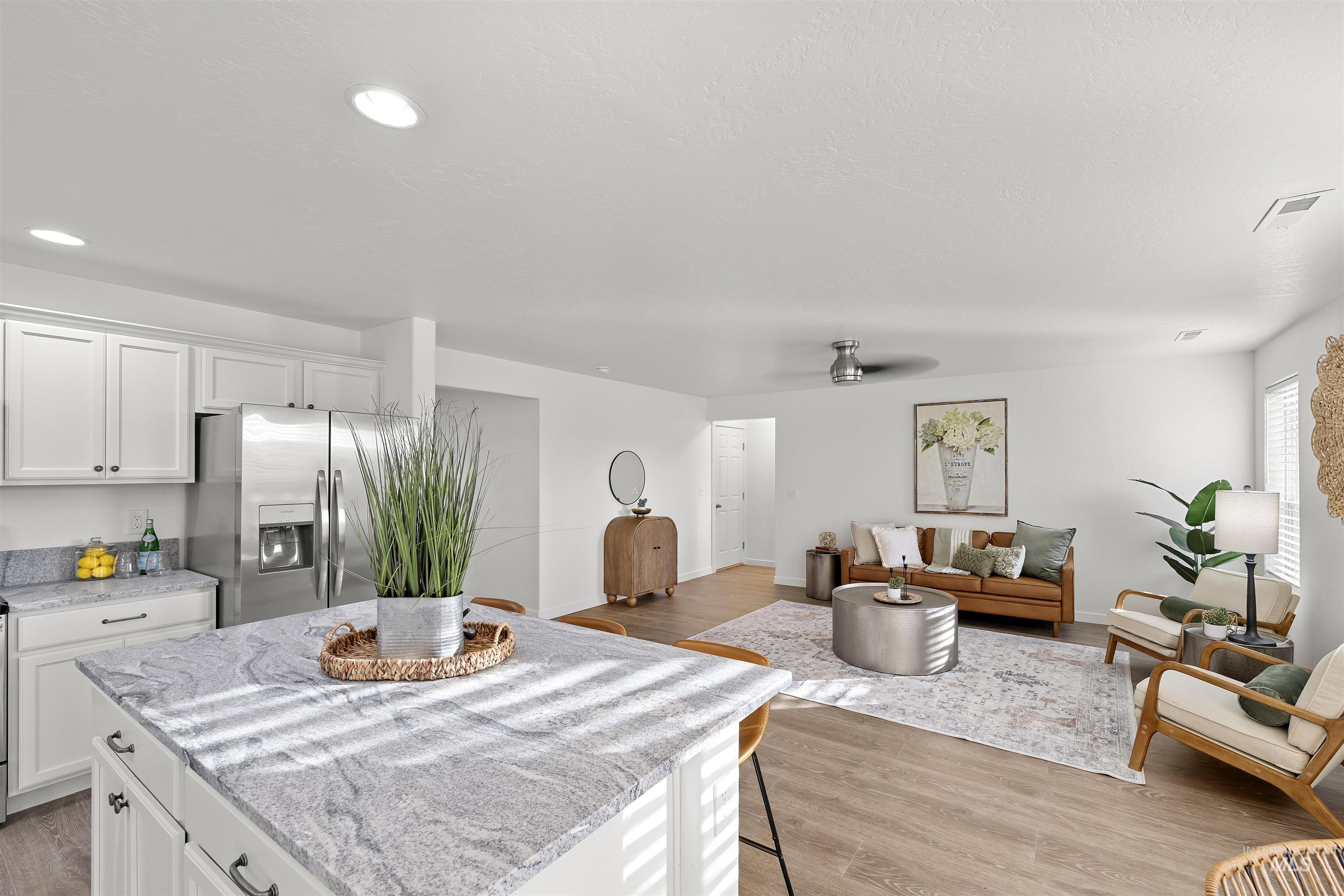 Kitchen featuring light stone counters, a kitchen breakfast bar, white cabinets, and recessed lighting