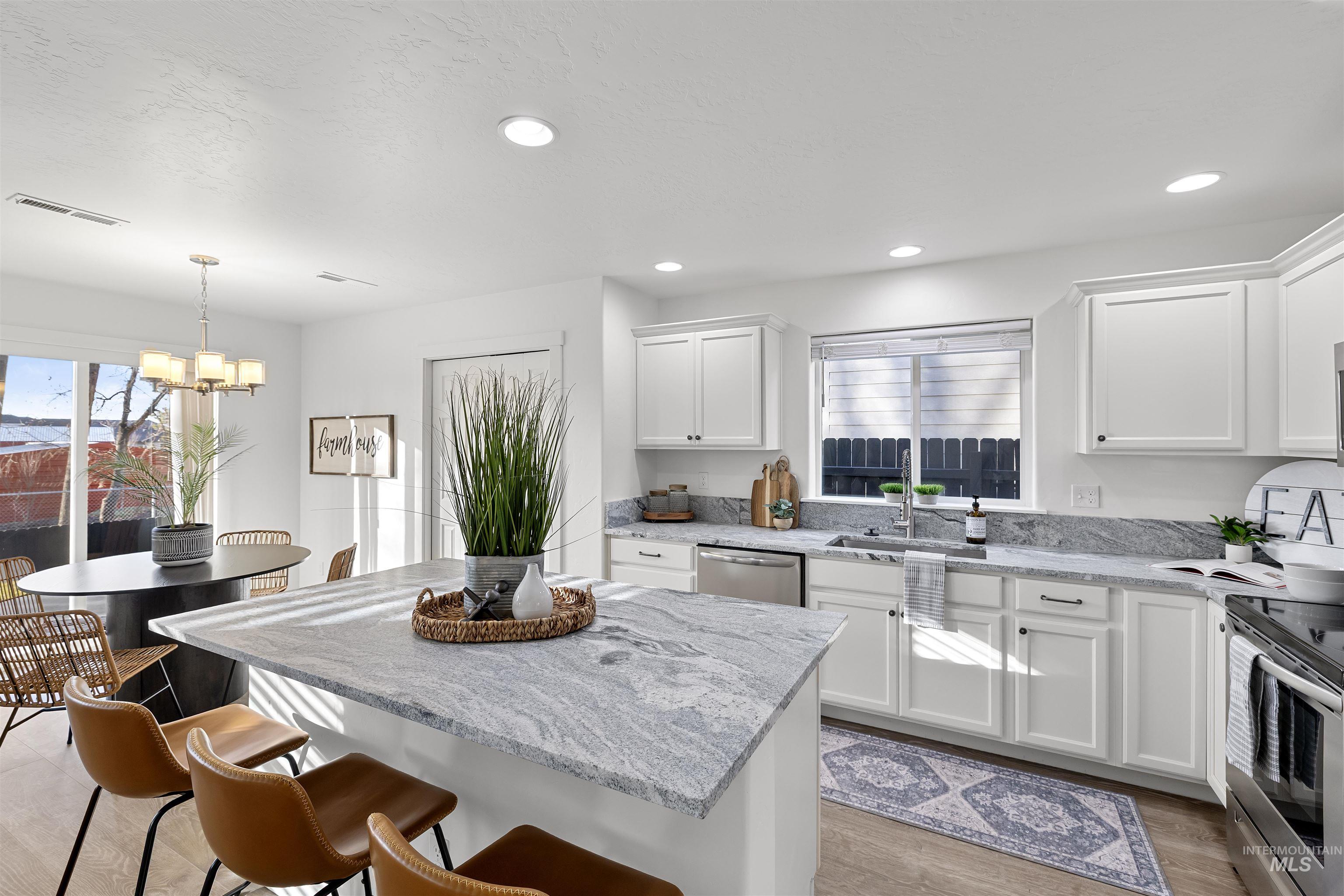 Kitchen featuring light wood finished floors, white cabinets, light stone countertops, a kitchen island, and appliances with stainless steel finishes