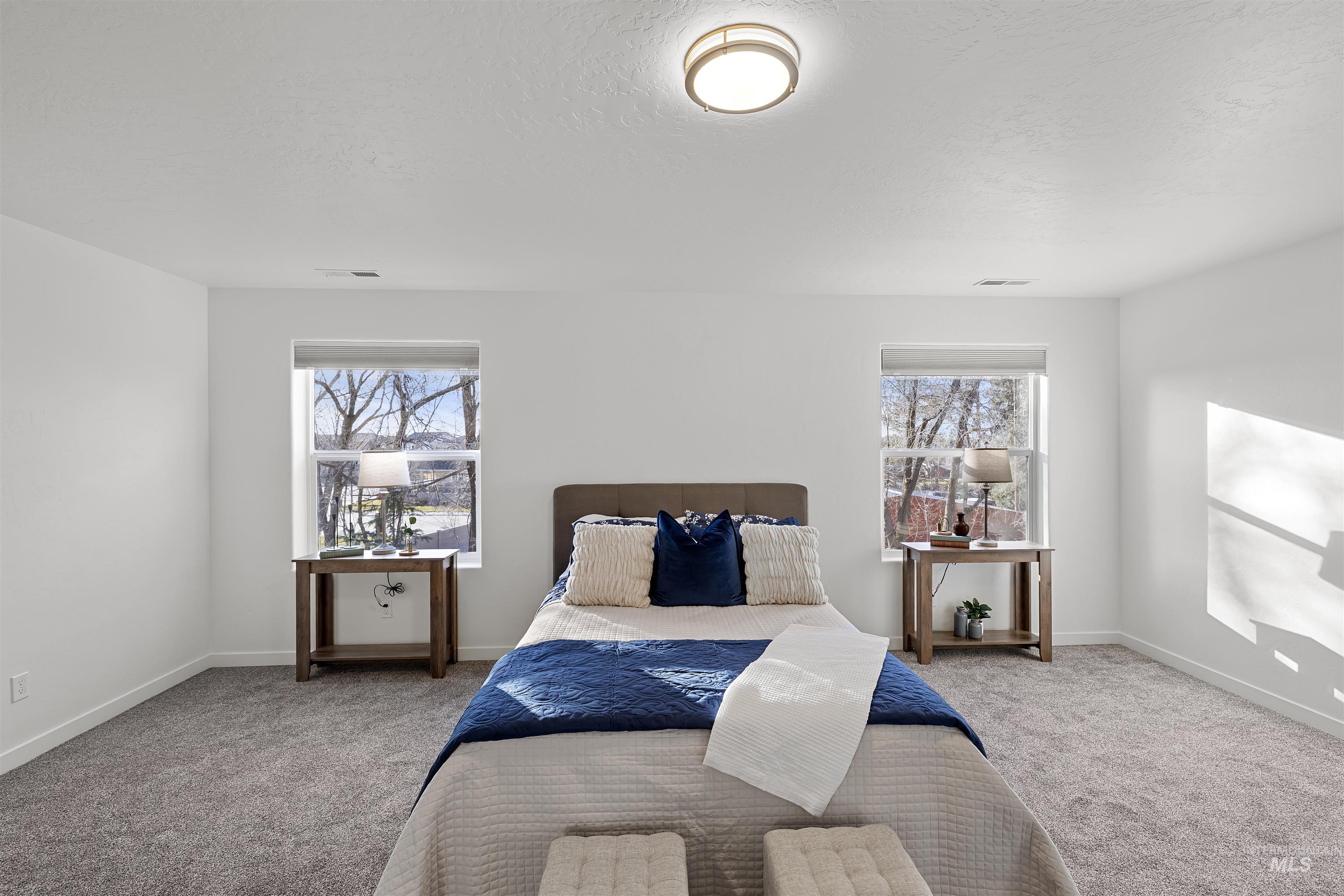 Carpeted bedroom with multiple windows and a textured ceiling