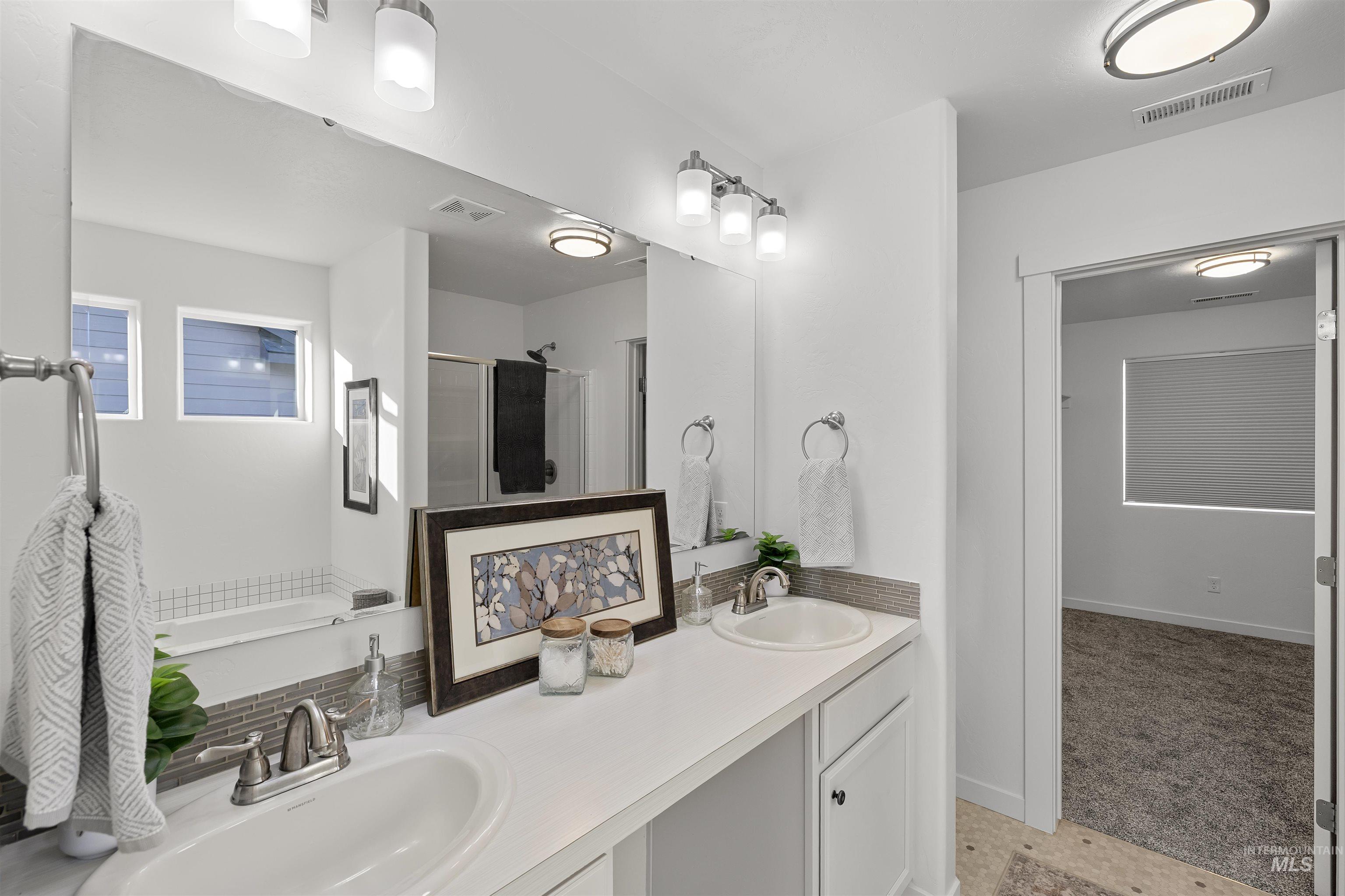 Bathroom featuring a shower stall and double vanity