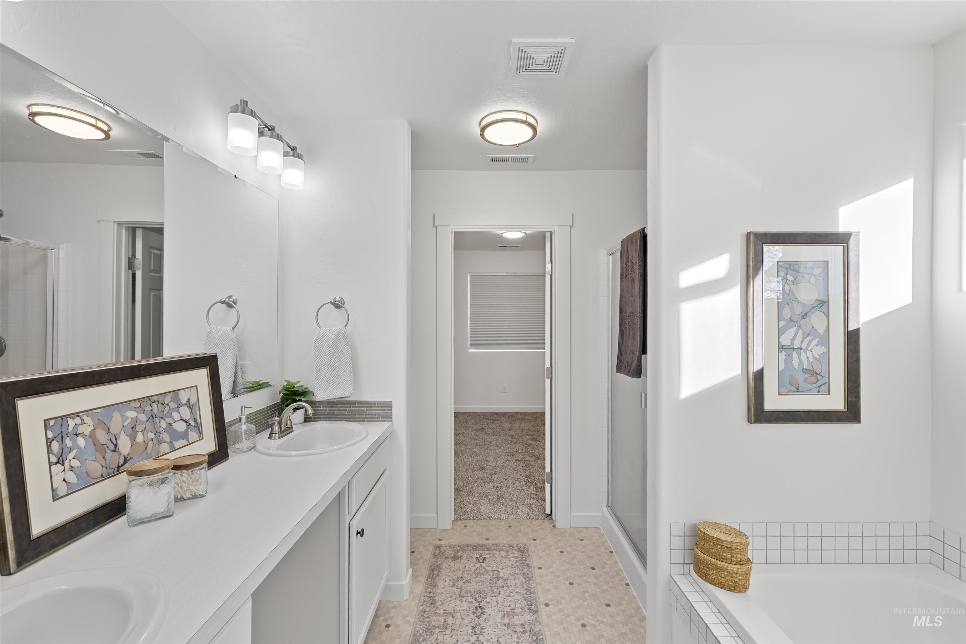 Bathroom featuring double vanity, a shower stall, and a relaxing tiled tub