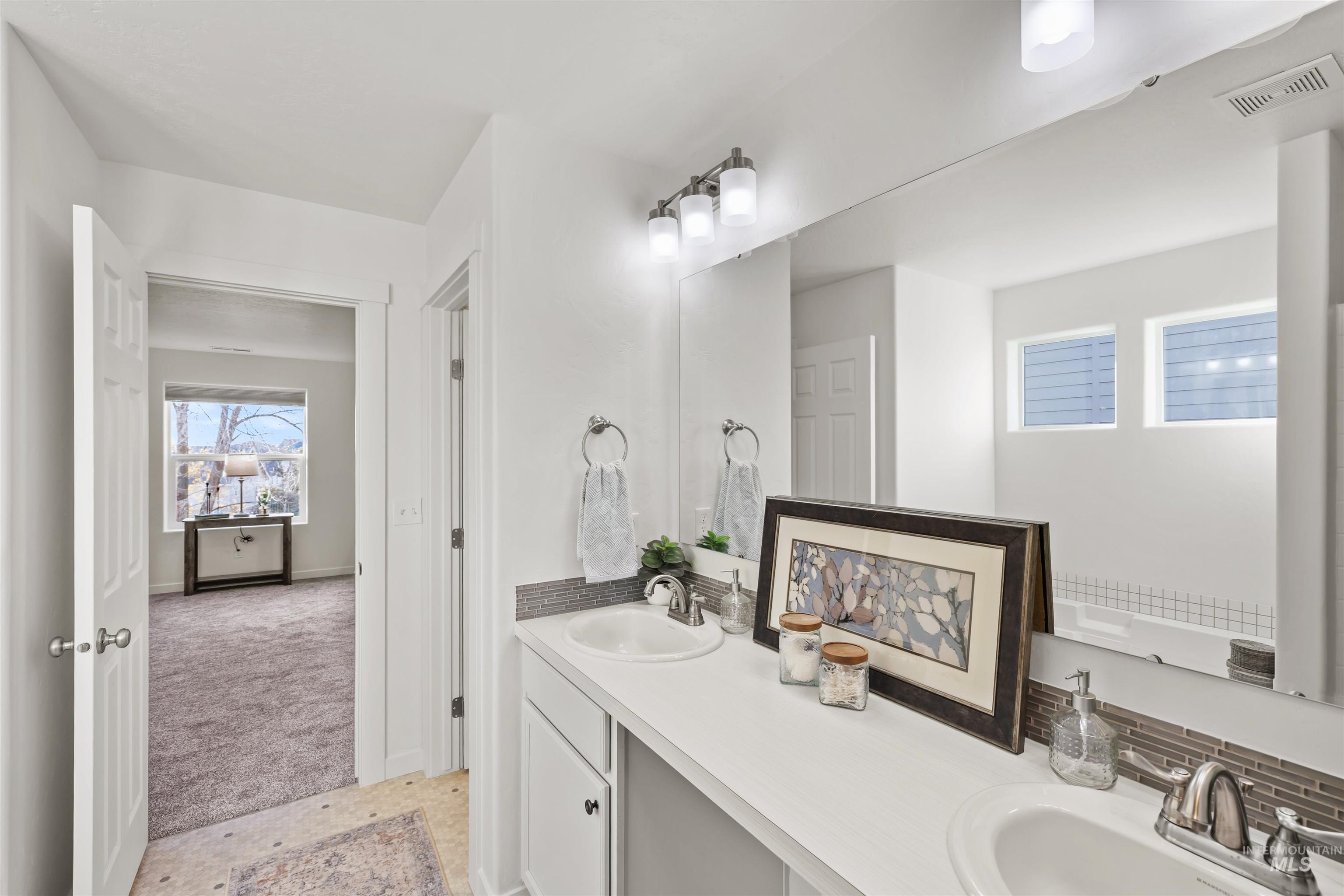 Bathroom featuring double vanity and light carpet