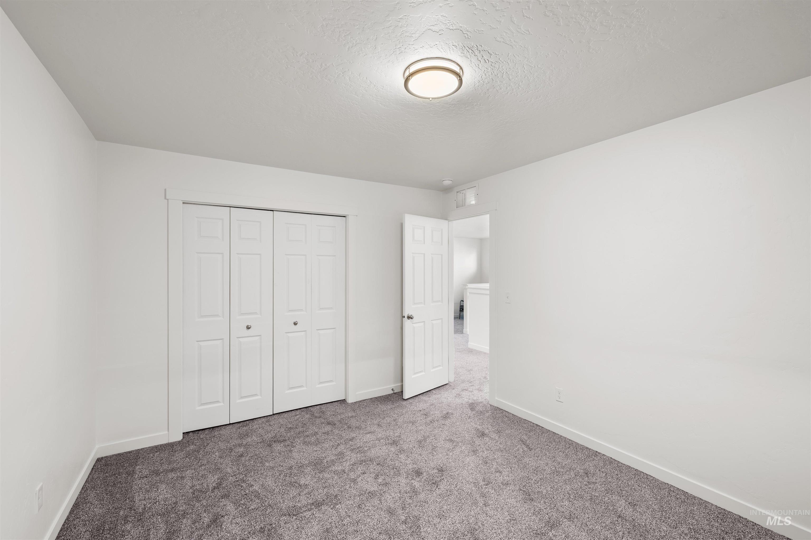 Unfurnished bedroom with a textured ceiling, carpet, and a closet