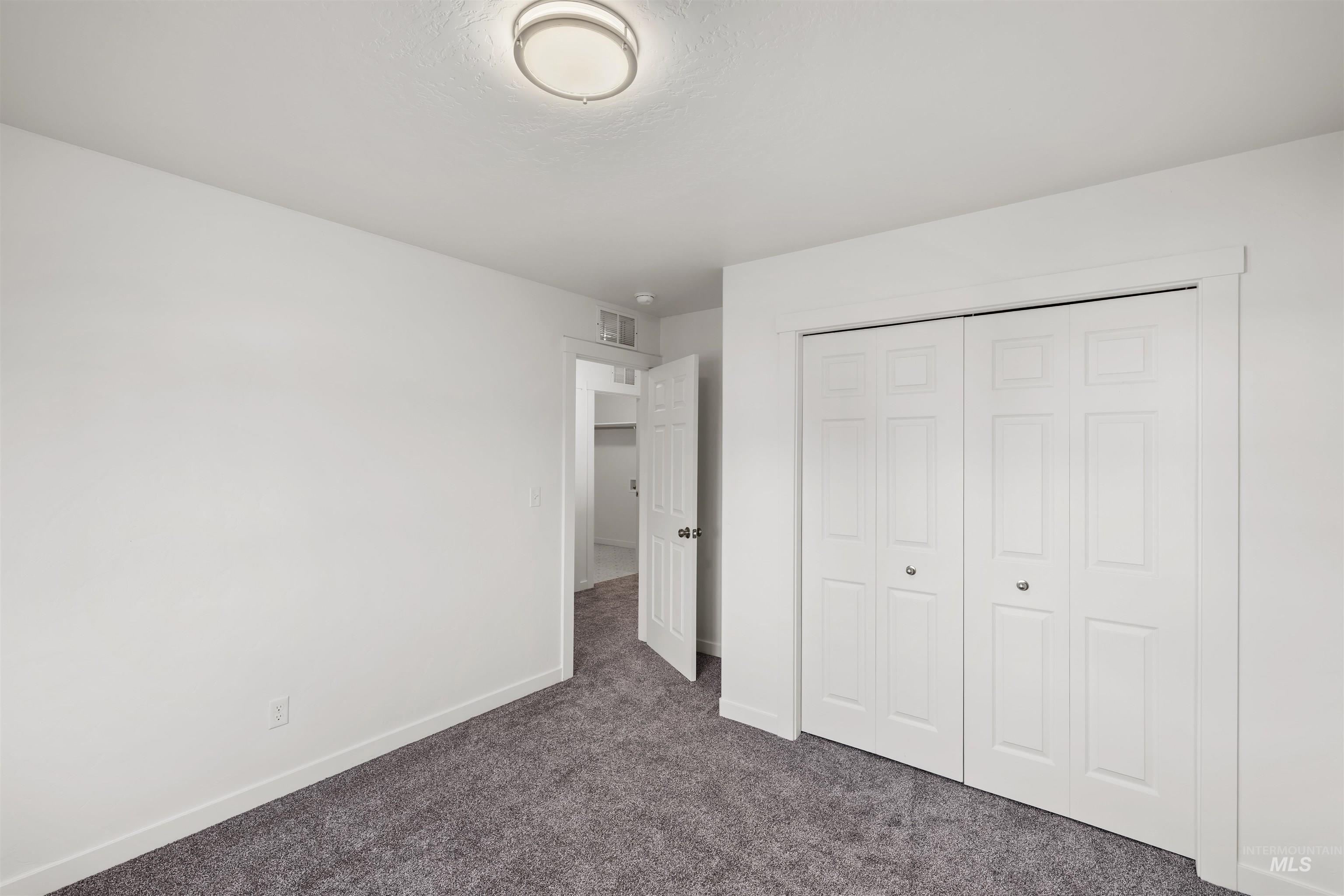 Unfurnished bedroom with dark colored carpet and a closet