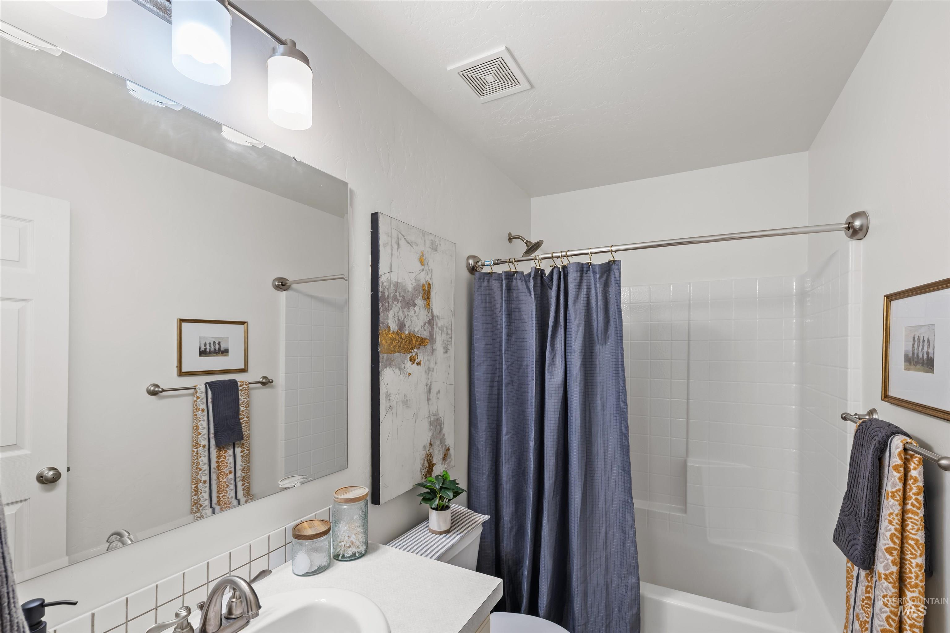 Bathroom with shower / bath combo with shower curtain and vanity