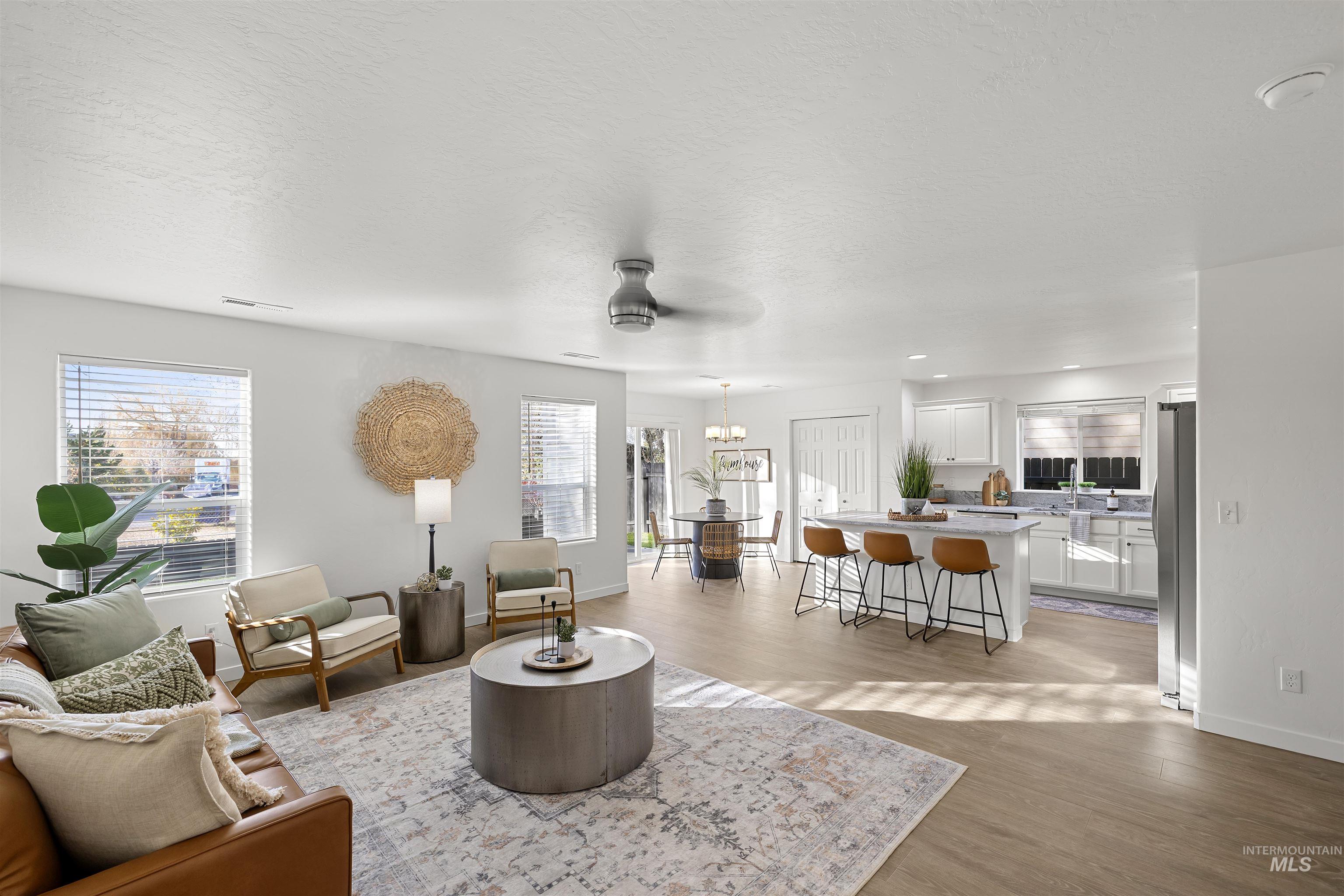 Living room featuring a ceiling fan, light wood-style flooring, a textured ceiling, and a chandelier