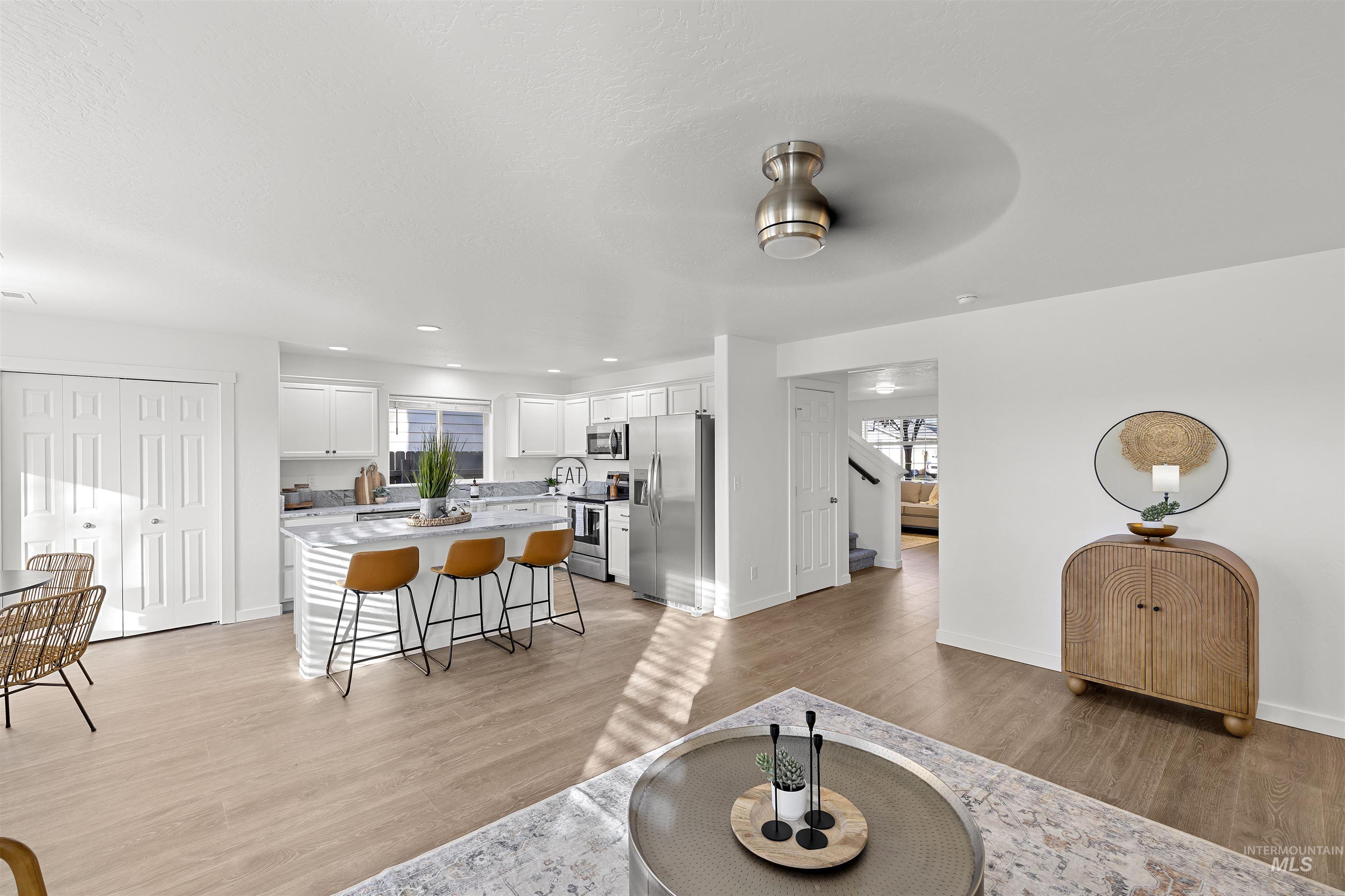 Living area with a ceiling fan, light wood finished floors, and recessed lighting