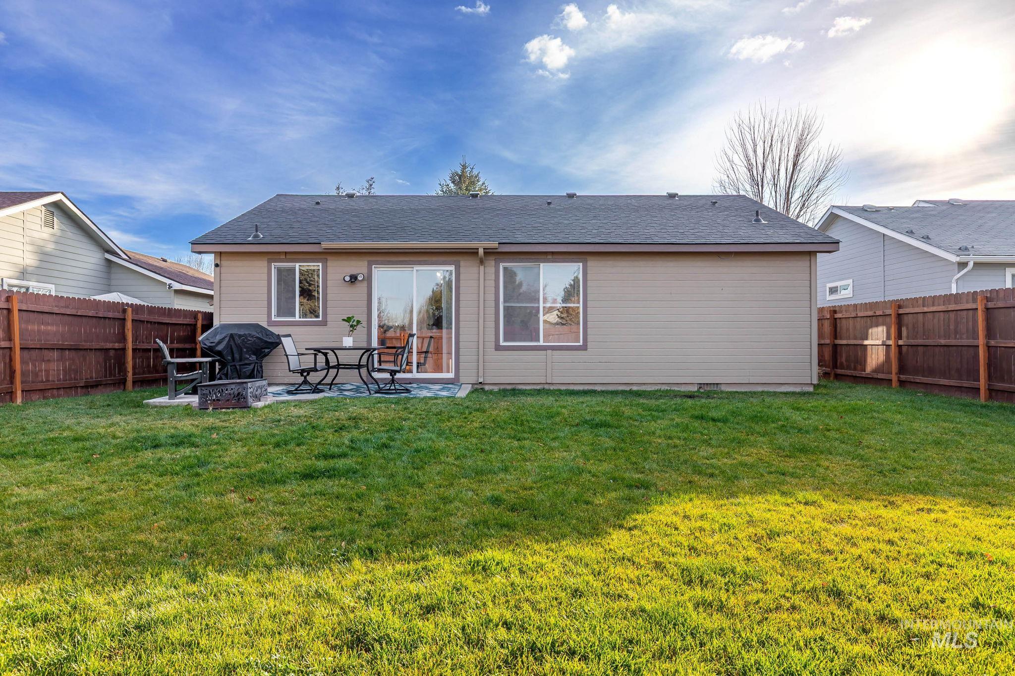 Rear view of property featuring a fire pit, a patio area, a fenced backyard, and roof with shingles