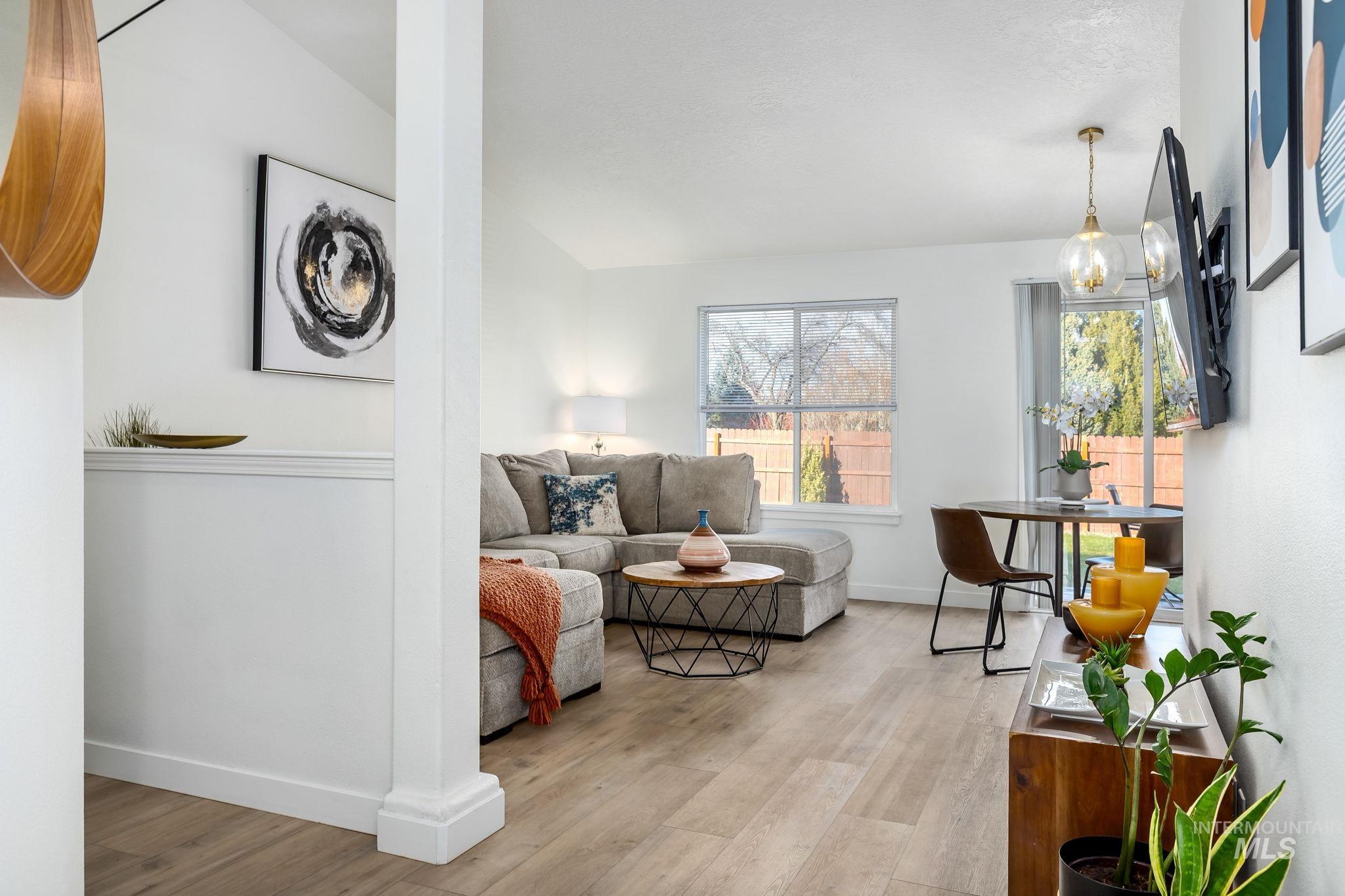 Living area featuring light wood finished floors, vaulted ceiling, and a chandelier