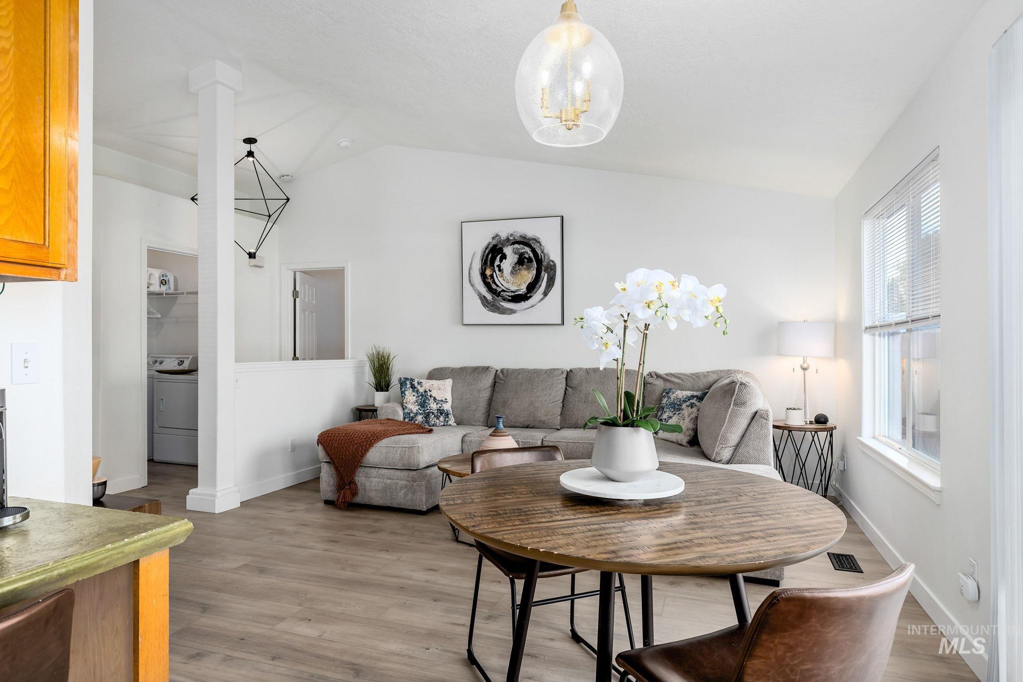 Dining area featuring lofted ceiling, light wood-style flooring, washer / dryer, and a chandelier