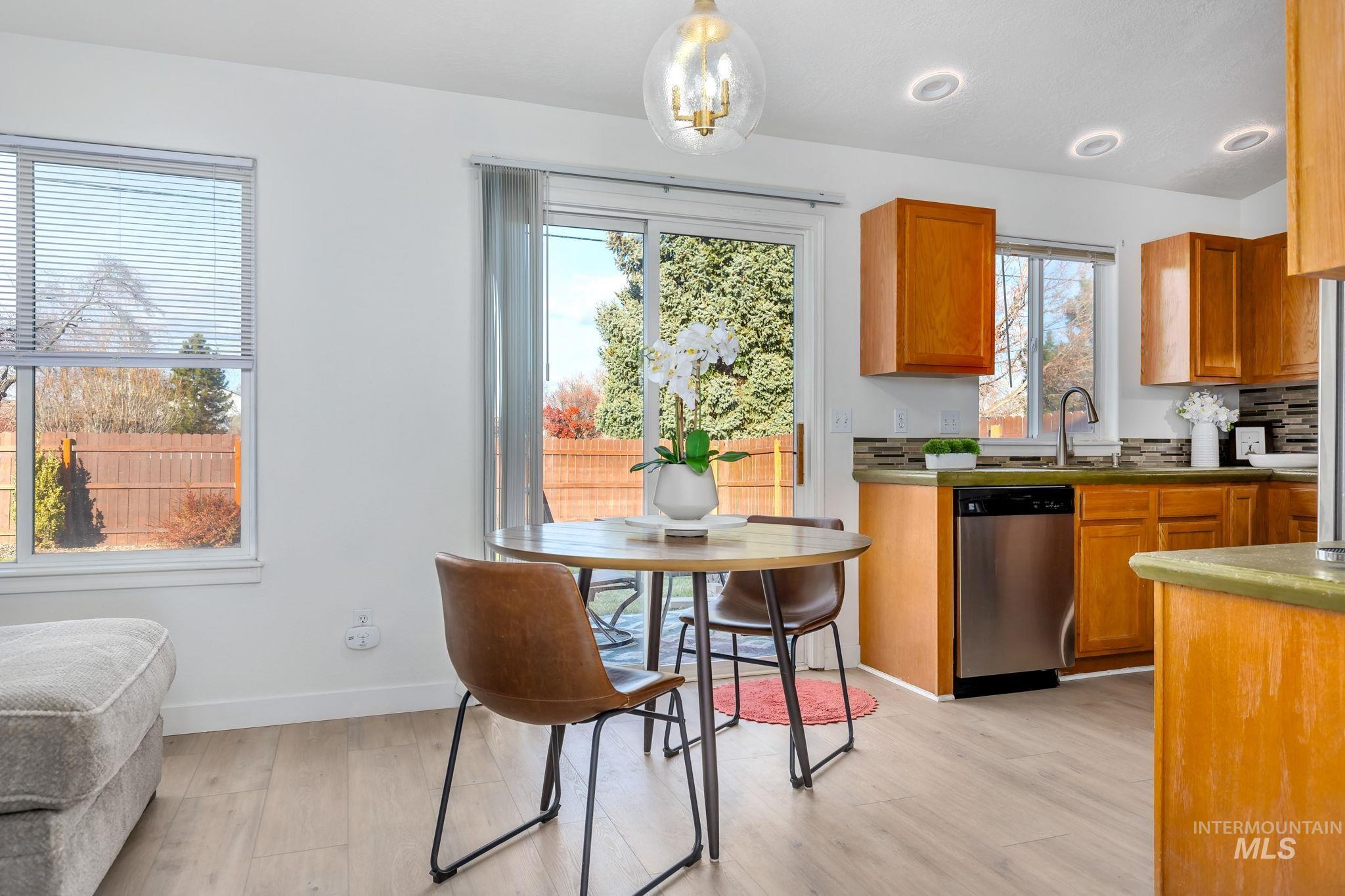 Kitchen featuring brown cabinetry, stainless steel dishwasher, light wood-style flooring, decorative light fixtures, and recessed lighting