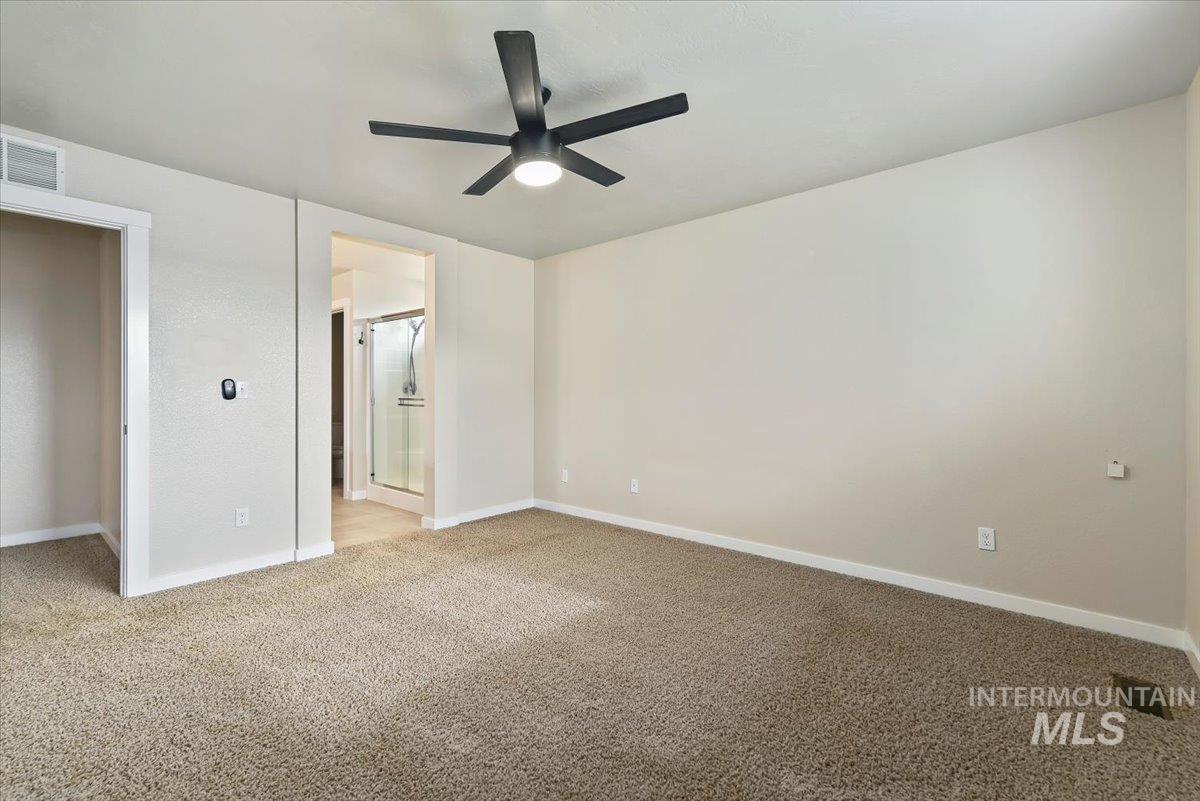 Unfurnished bedroom with light carpet, a ceiling fan, and ensuite bath