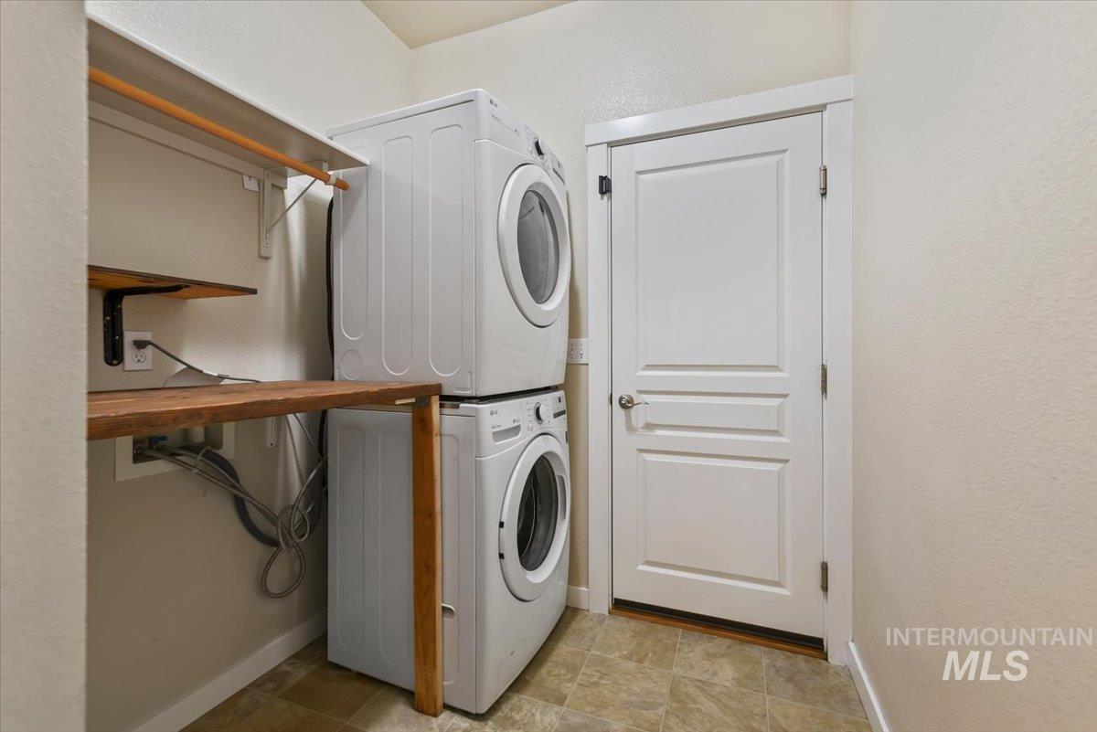 Laundry room with a textured wall and stacked washer and clothes dryer