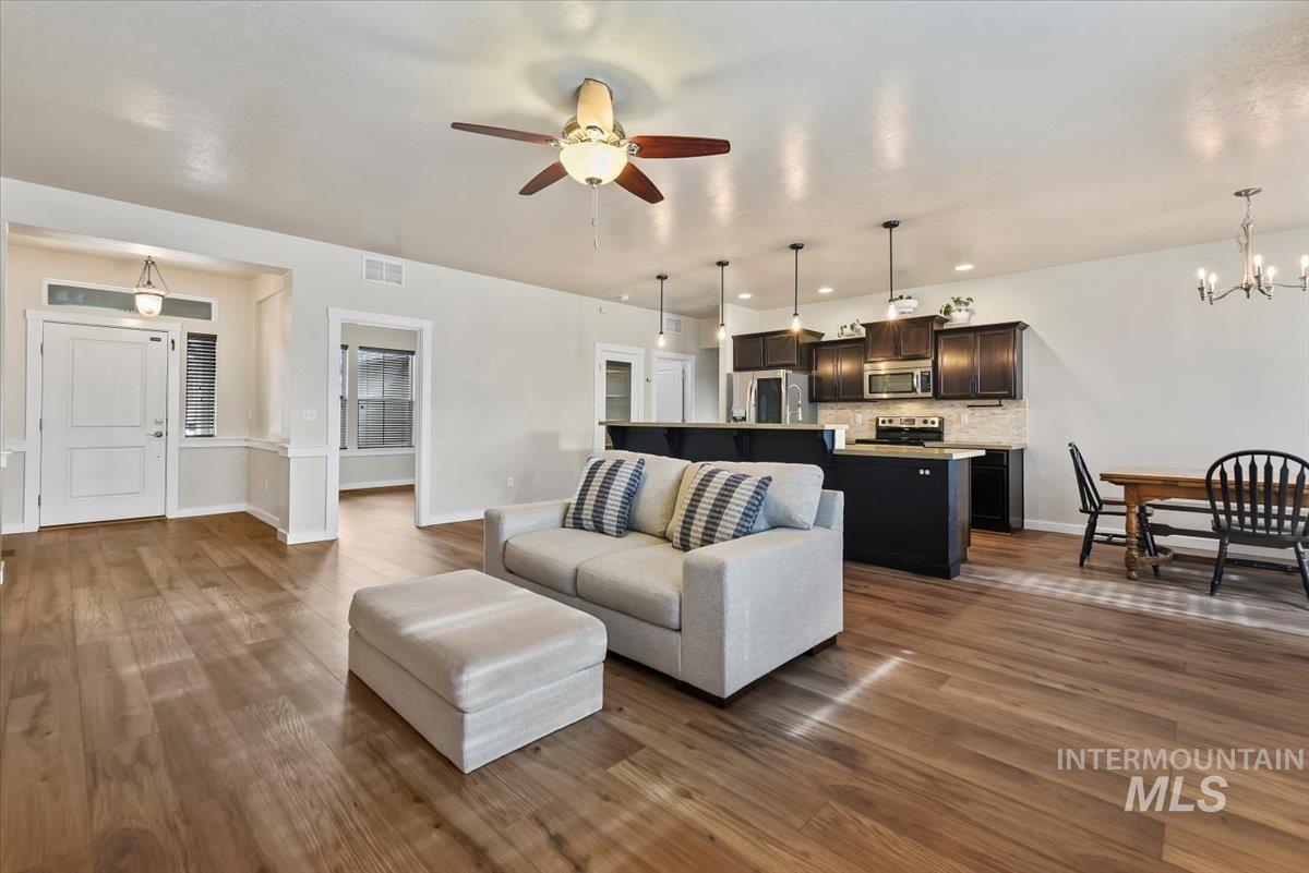 Living area with a chandelier, dark wood-type flooring, and a ceiling fan