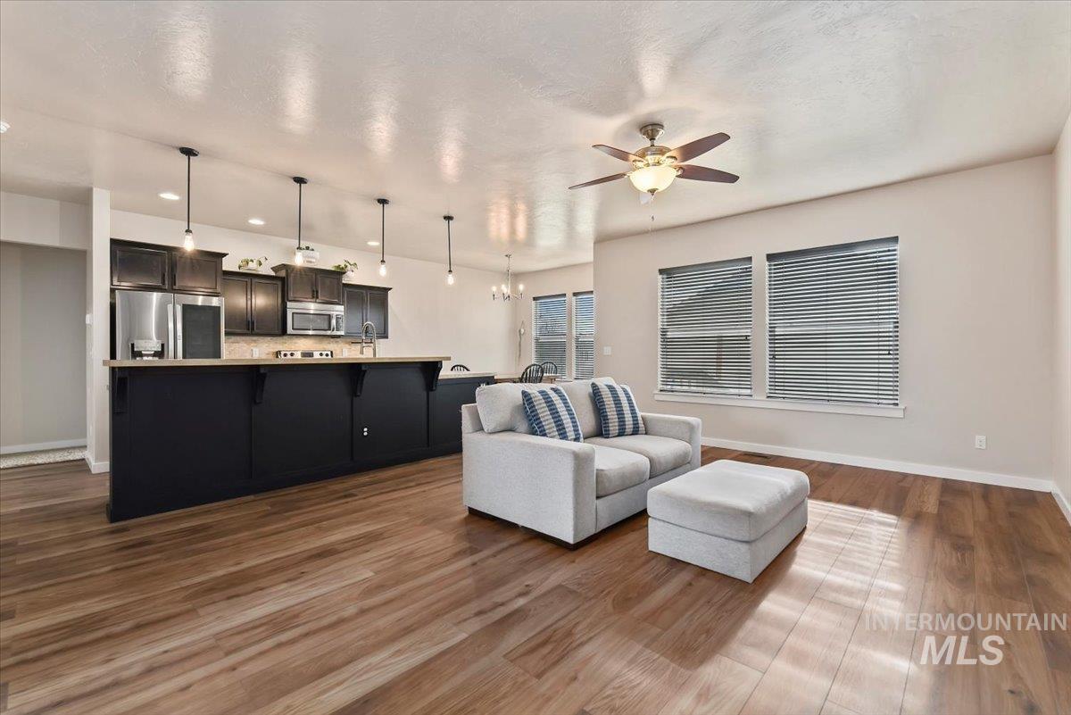 Living area with a chandelier, ceiling fan, and dark wood-style floors