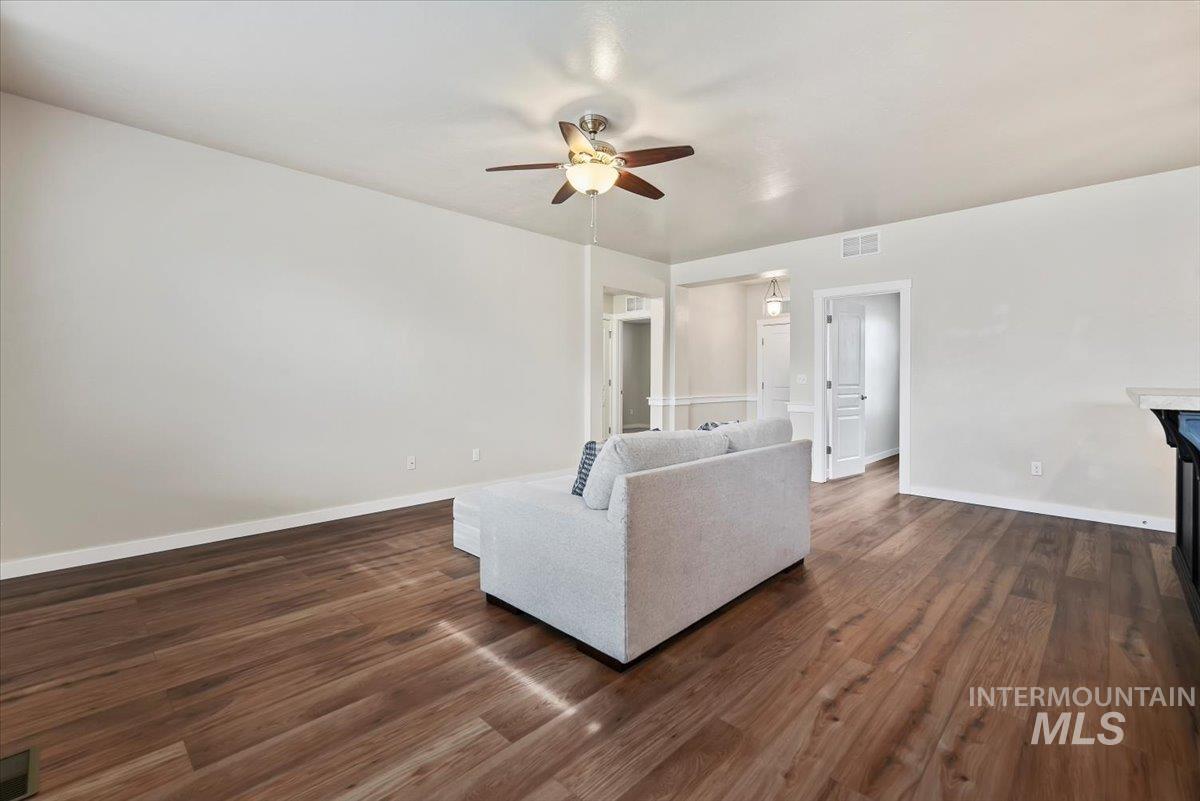 Living area with dark wood-type flooring, a ceiling fan,