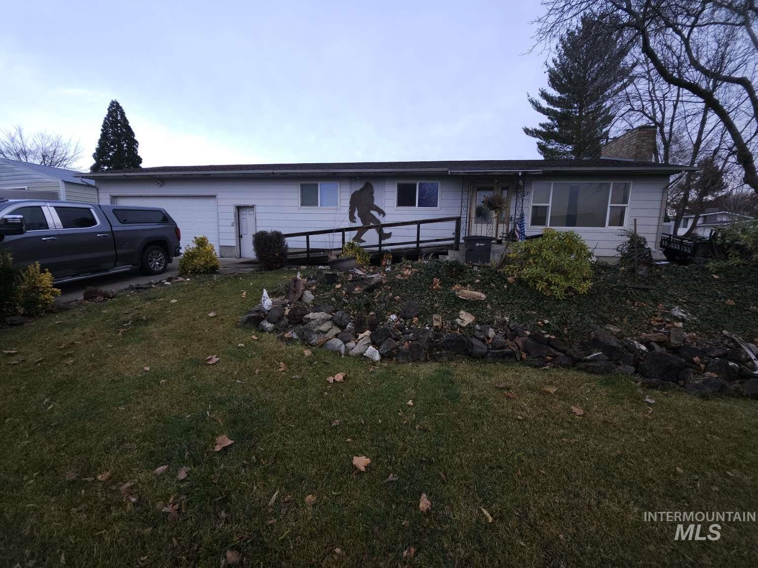View of front facade featuring a front lawn, a garage, and a chimney