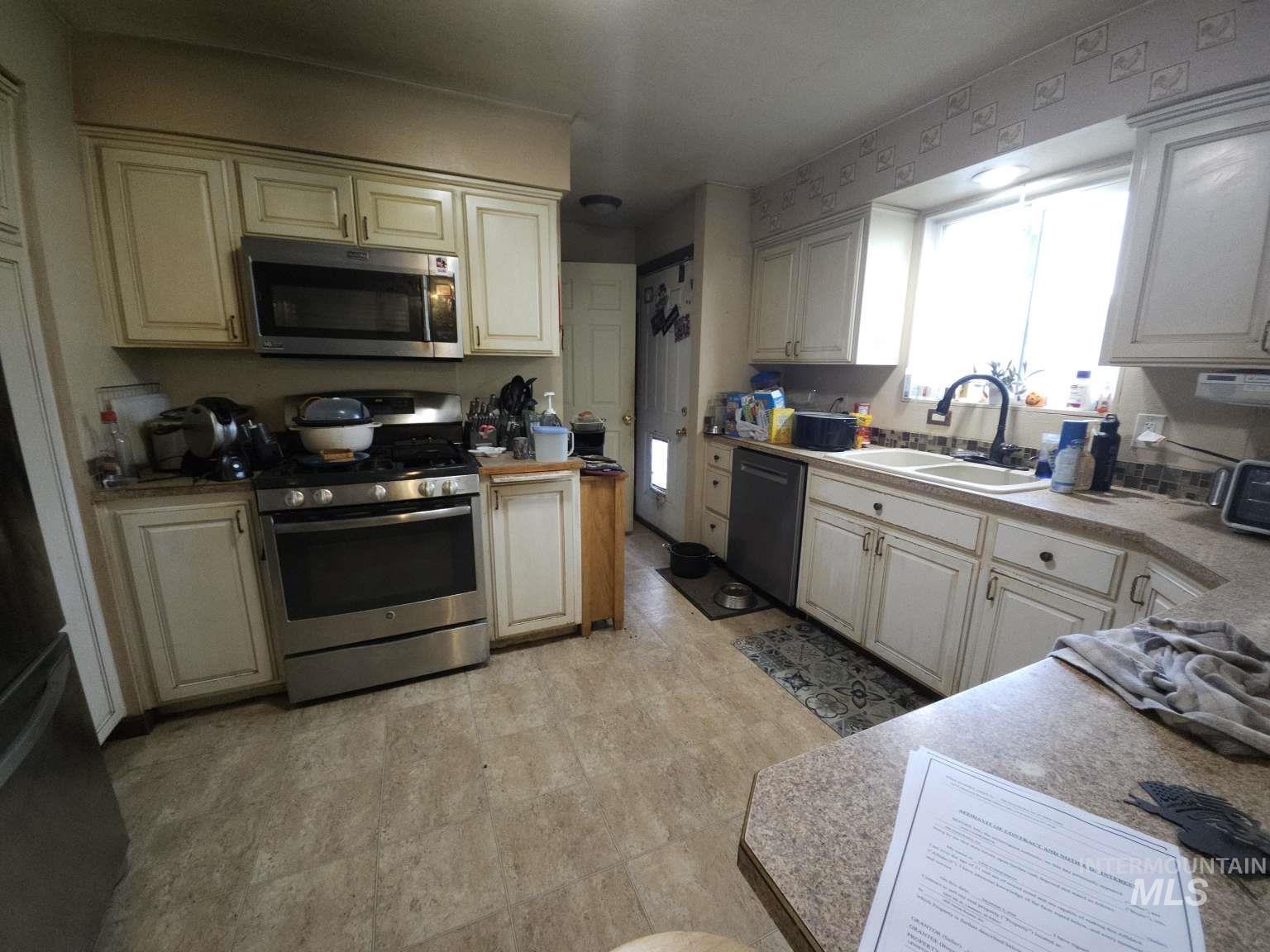 Kitchen with appliances with stainless steel finishes and light countertops