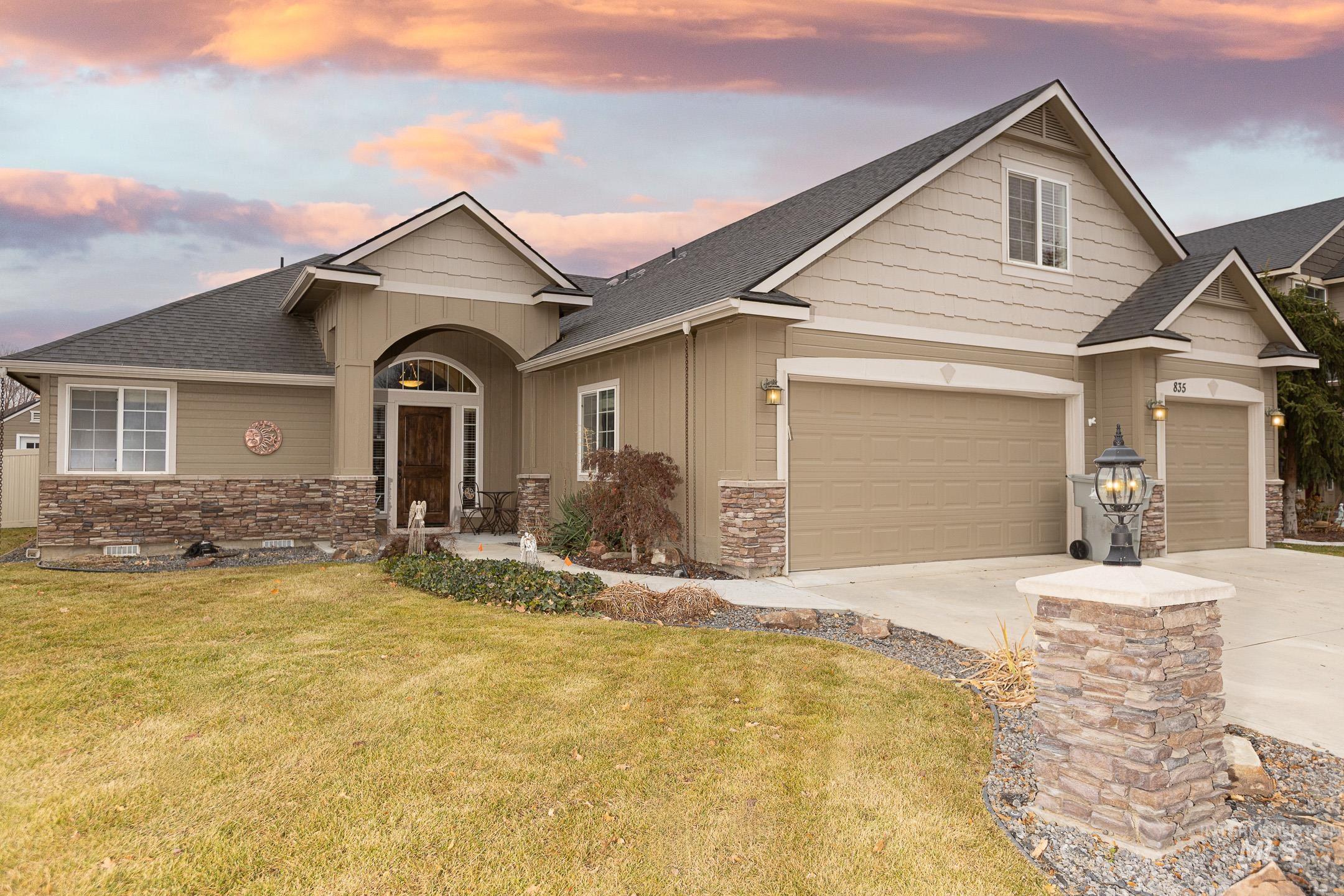 Craftsman-style home featuring stone siding, roof with shingles, a front yard, and concrete driveway