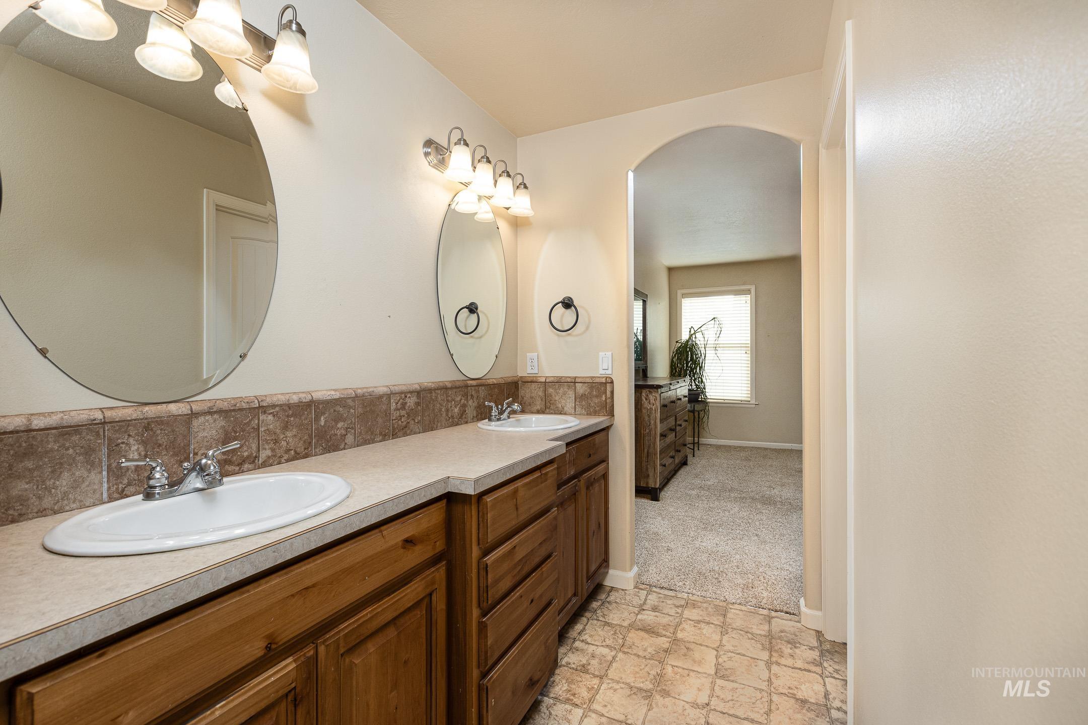 Bathroom featuring stone finish flooring, double vanity, and light colored carpet