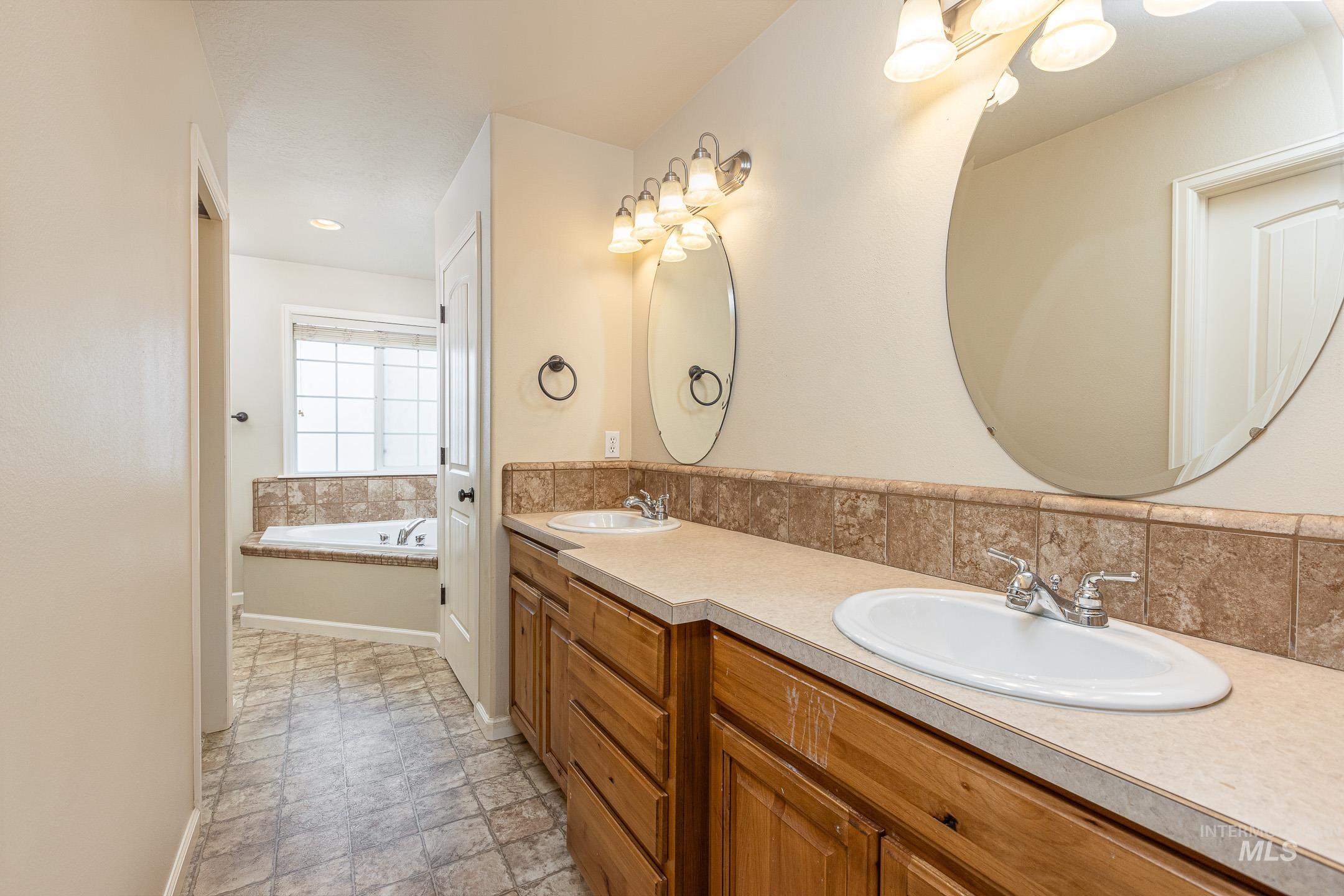 Full bath featuring double vanity and a garden tub
